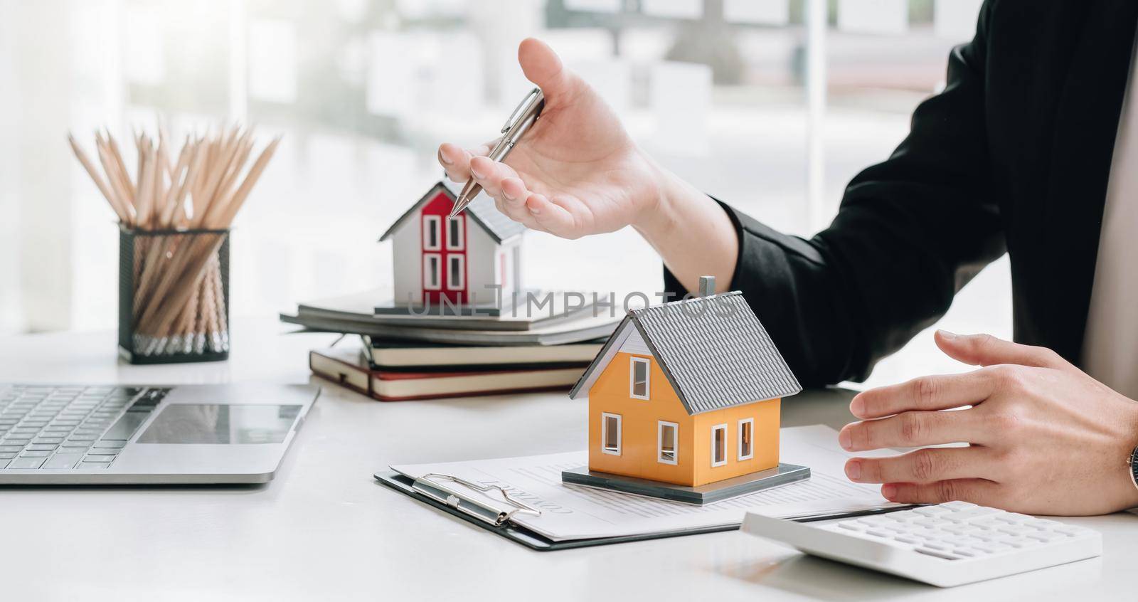 Real estate broker agent presenting and consult to customer to decision making sign insurance form agreement, buy and sell home model, concerning mortgage loan offer for and house insurance.