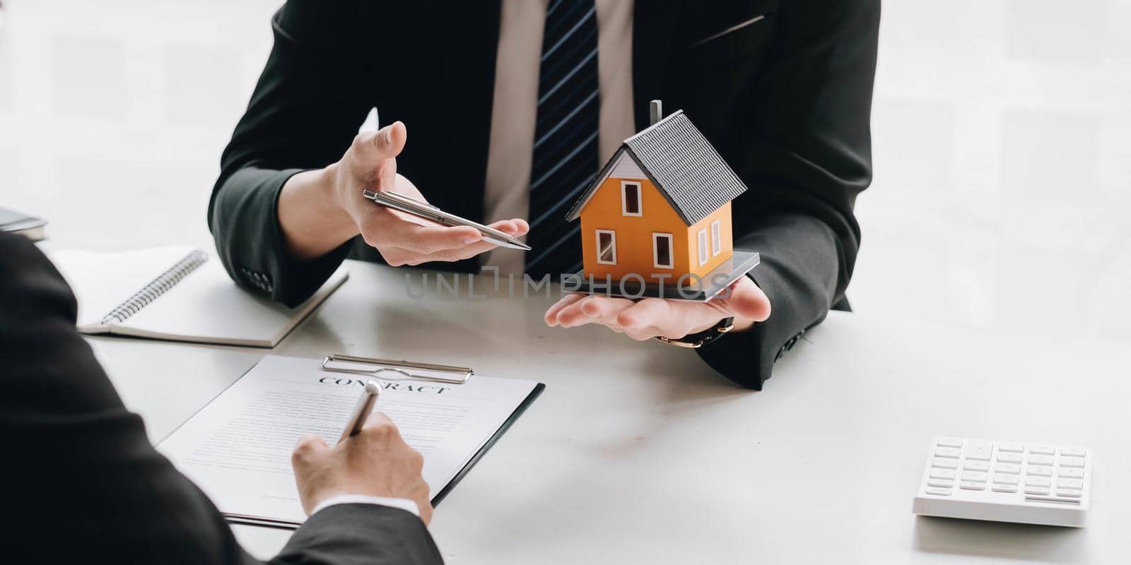 Real estate broker agent presenting and consult to customer to decision making sign insurance form agreement, buy and sell home model, concerning mortgage loan offer for and house insurance.