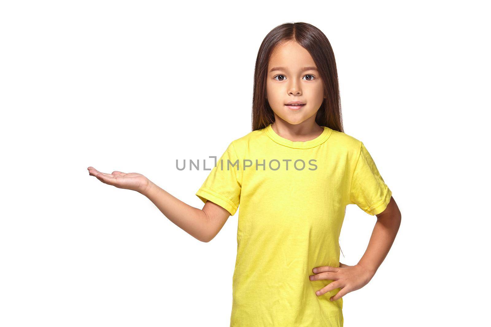 Little girl in yellow t-shirt holding her hand out and showing copy space for your product isolated on white background