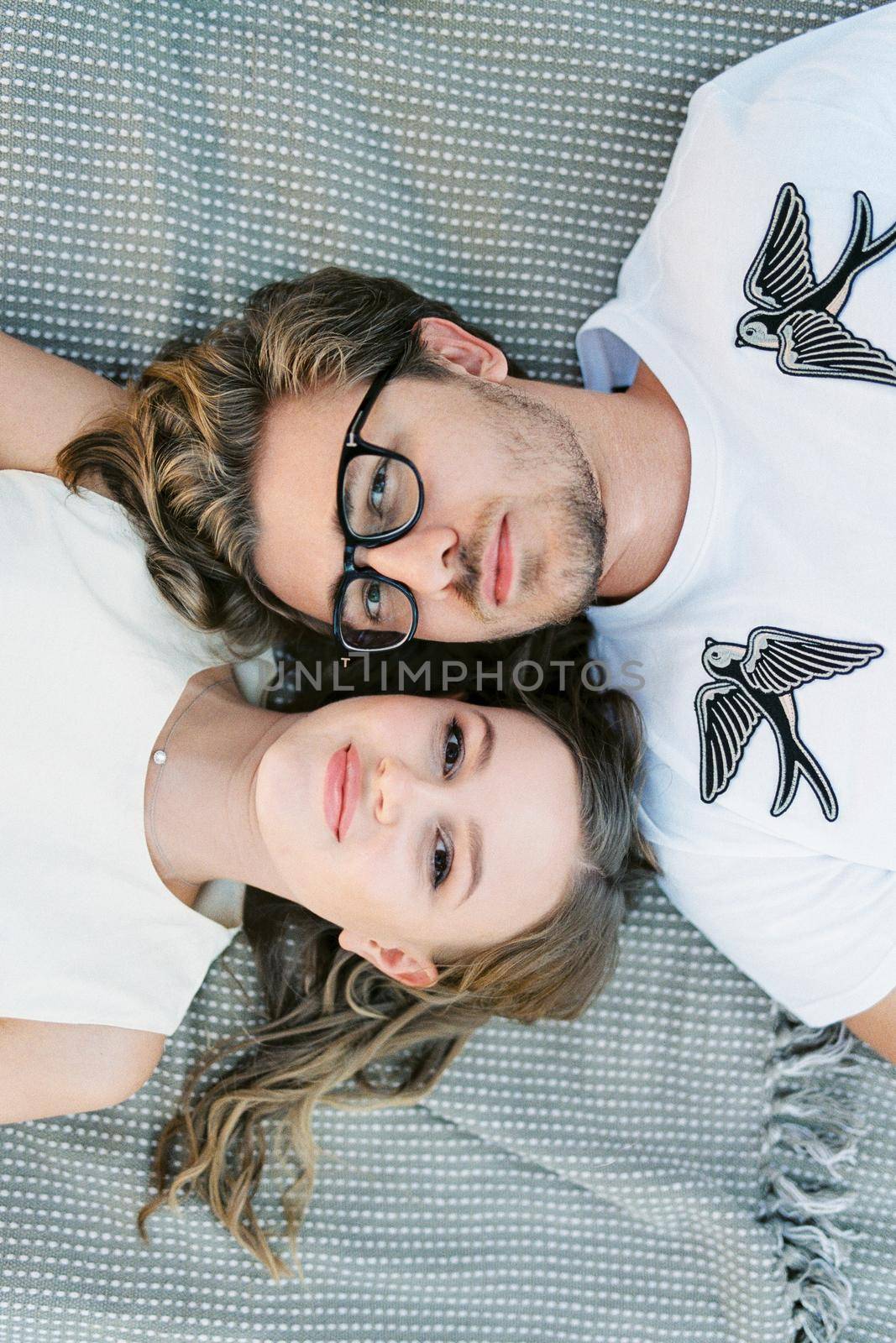 Man and woman lie head to head on a blanket. Top view. High quality photo