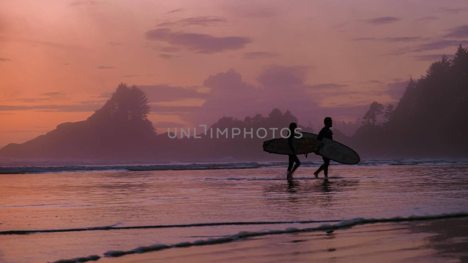 Tofino Vancouver Island Pacific rim coast, surfers with board during sunset at the beach by fokkebok