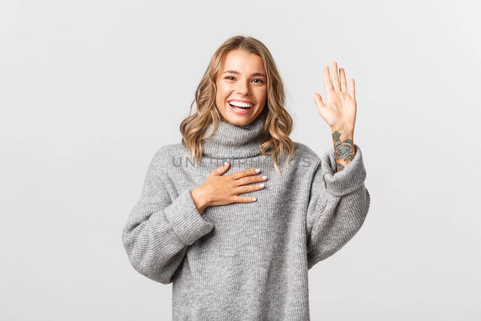 Image of happy honest girl raising one arm and put hand on heart, making promise, swear and telling truth, standing over white background by Benzoix