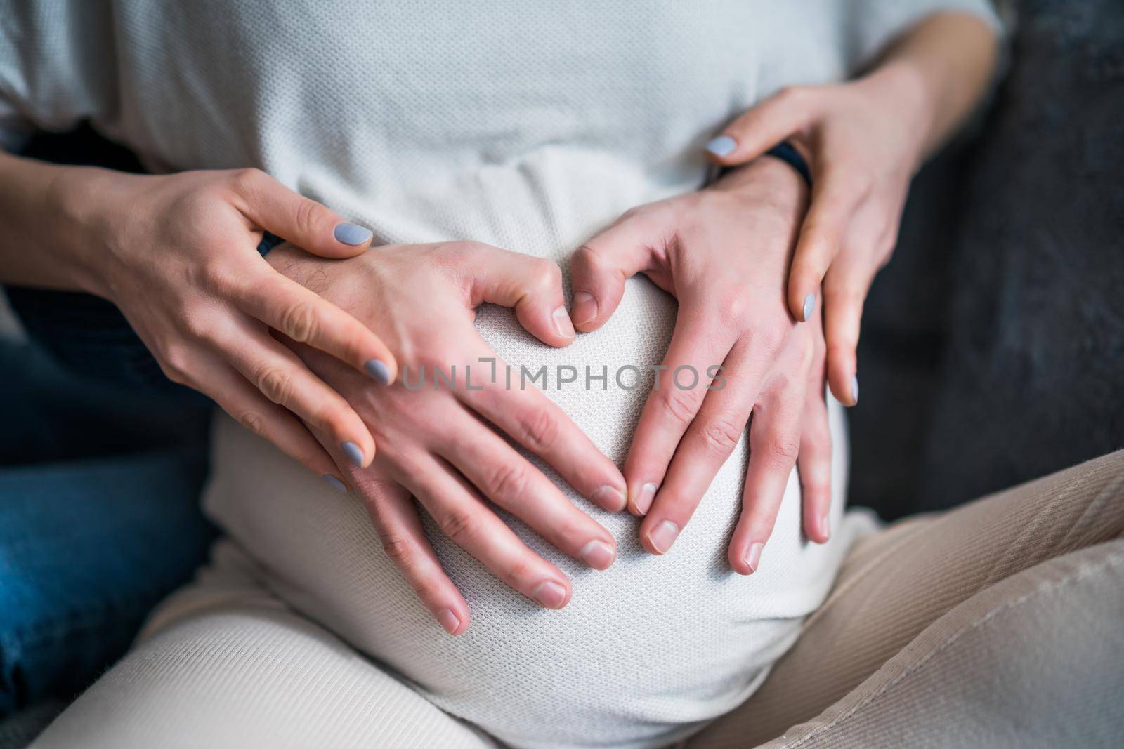 Close up image of pregnant woman stomach. Man is embracing stomach of his pregnant wife.