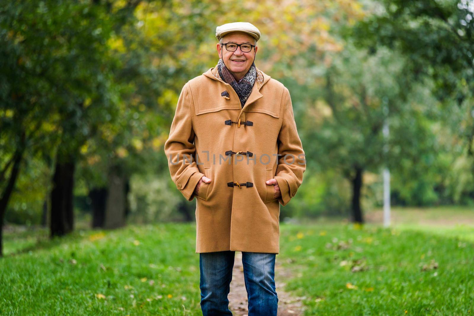 Happy senior is walking in park in autumn.