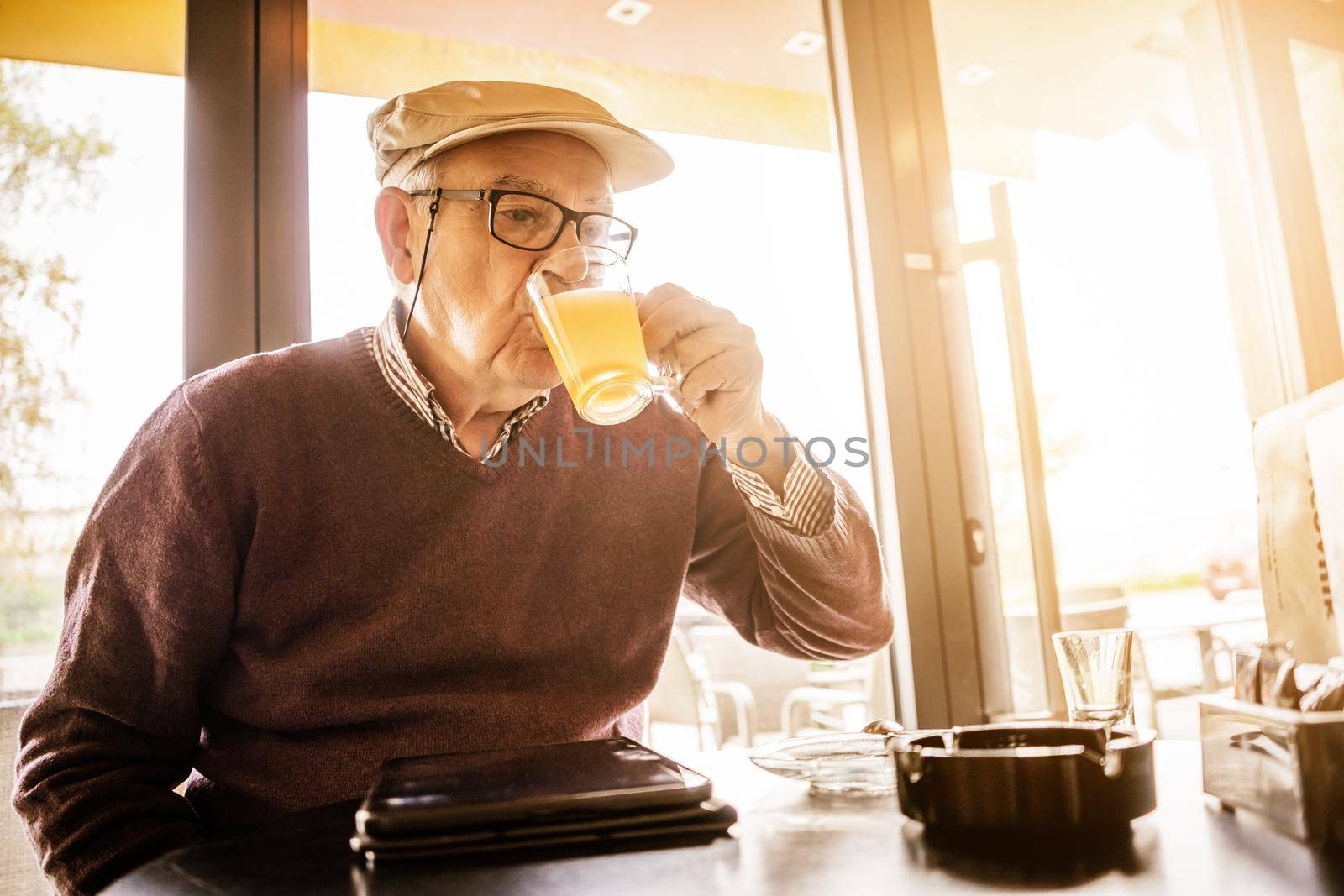 Senior man is sitting in cafe and drinking tea.