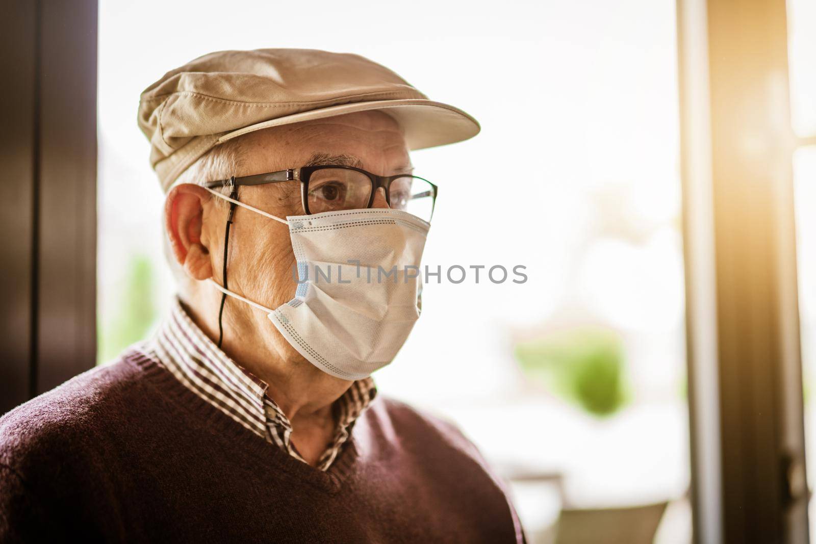 Indoor close up portrait of senior man who is wearing face protection mask. Covid 19 prevention concept.