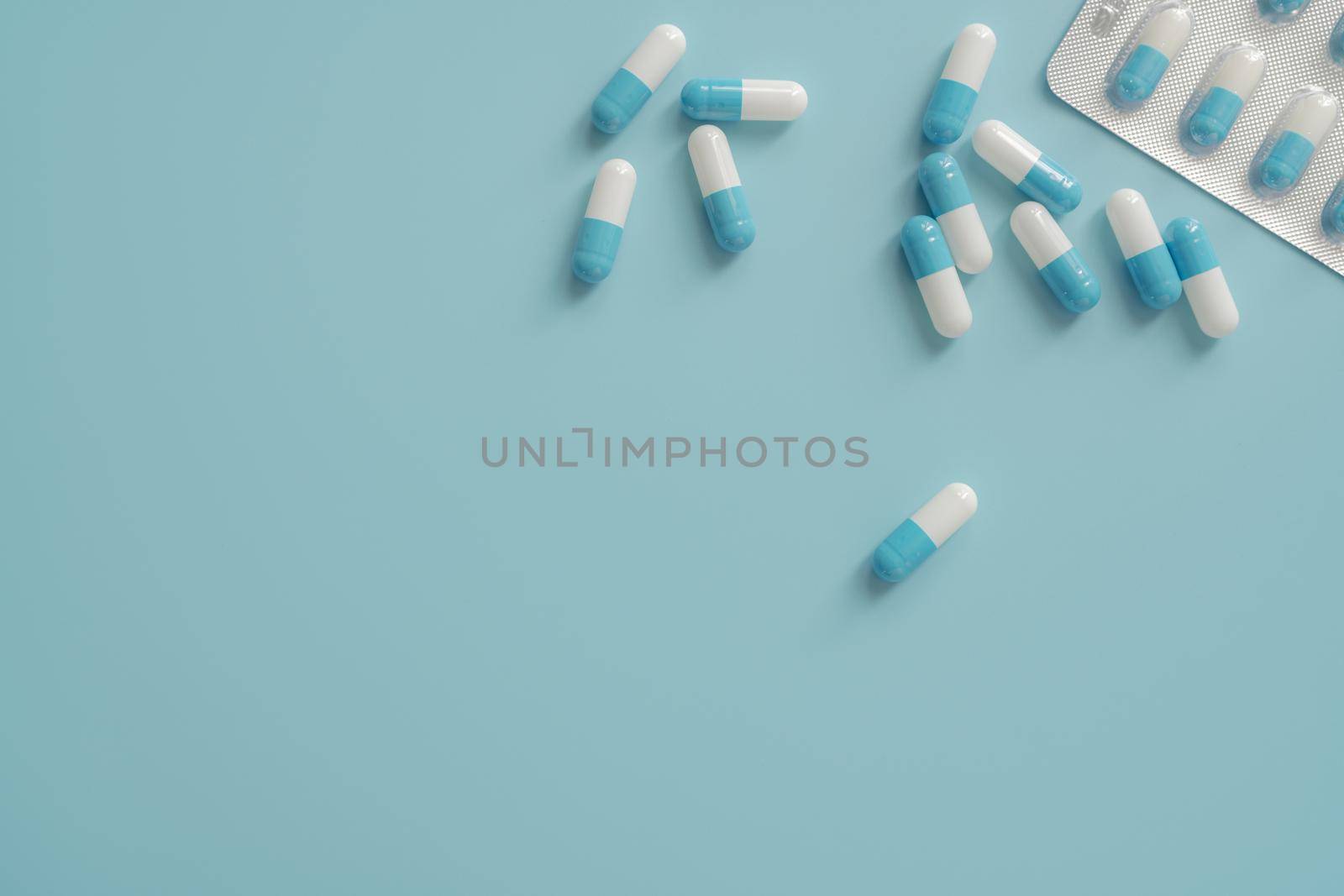 Antibiotic capsule pills on blue background. Prescription drugs. Blue-white capsule pills. Antibiotic drug resistance concept. Pharmaceutical industry. Superbug problems. Medicament and pharmacology.