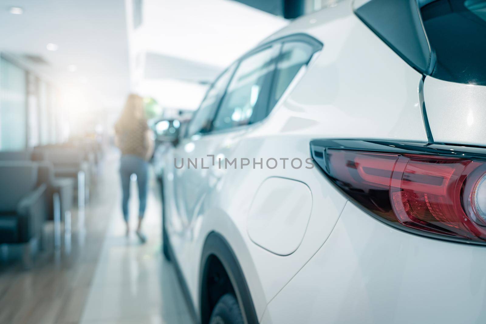 Closeup tail light of white SUV car parked in luxury showroom. Car dealership office. Rear view new car in modern showroom. Car for sale. Automobile leasing and insurance. Dealer agent business.