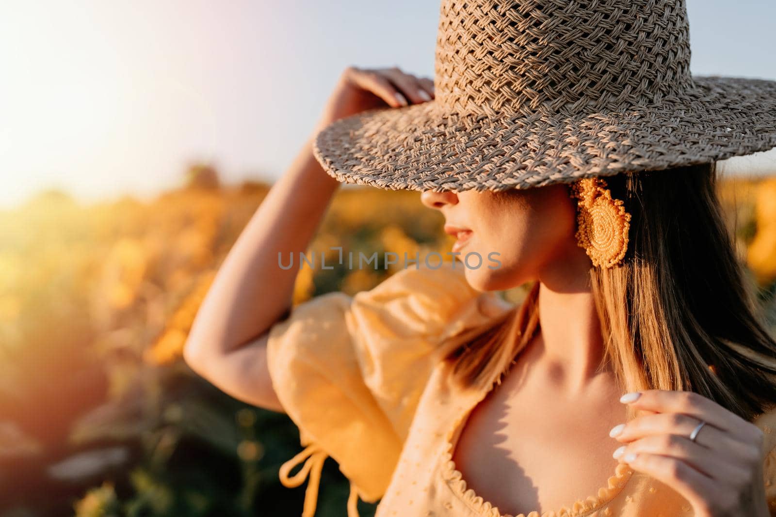 Mysterious stranger woman in straw hat posing on sunflowers background. Blooming field. Vintage retro style outfit. by kristina_kokhanova