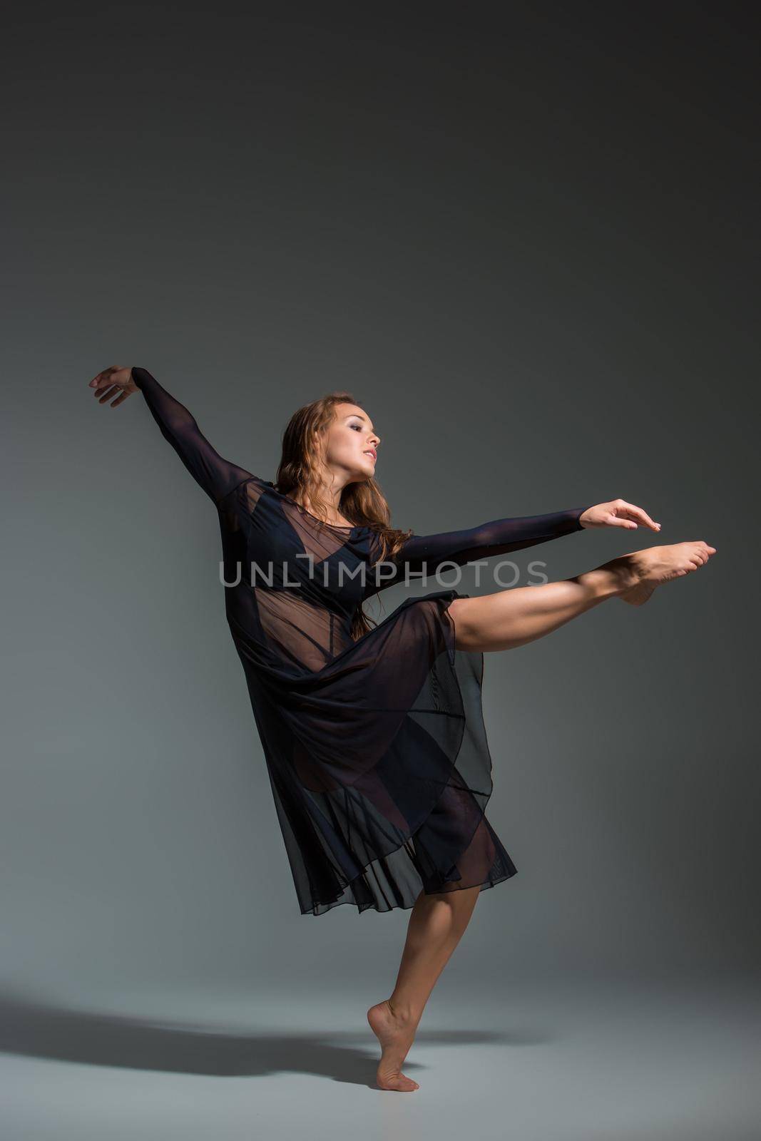 Dancing woman in a black dress. Contemporary modern dance on a gray background. by nazarovsergey