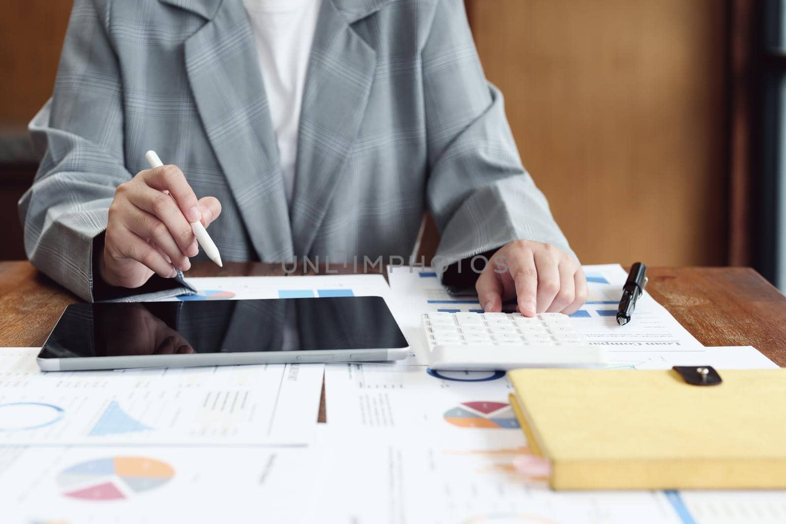 Business woman using calculator, tablet and documents to work.