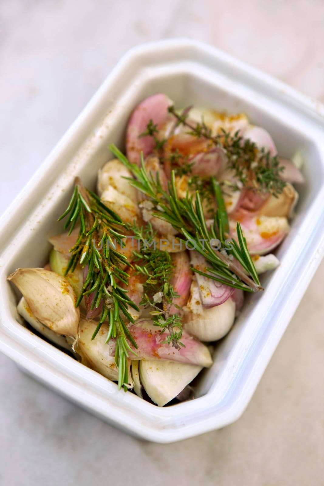 Garlic, onions, shallots and various herbs in a porcelain dish before cooking