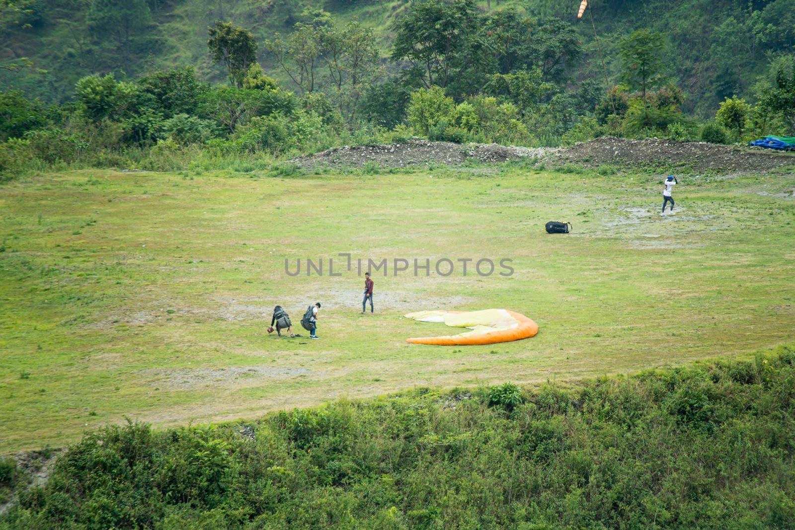 landing site for para gliding people with folded parachute ground support people and a green platue to land safely in Bhimtal India Asia by Shalinimathur