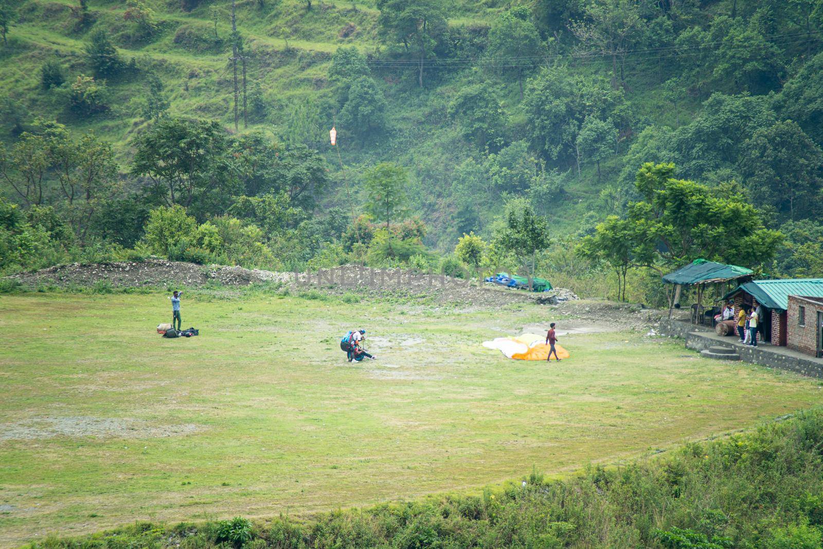 landing site for para gliding people with folded parachute ground support people and a green platue to land safely in Bhimtal India Asia by Shalinimathur