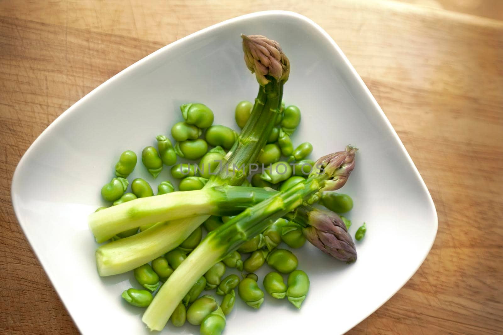 Violet asparagus and green peas in a porcelain dish