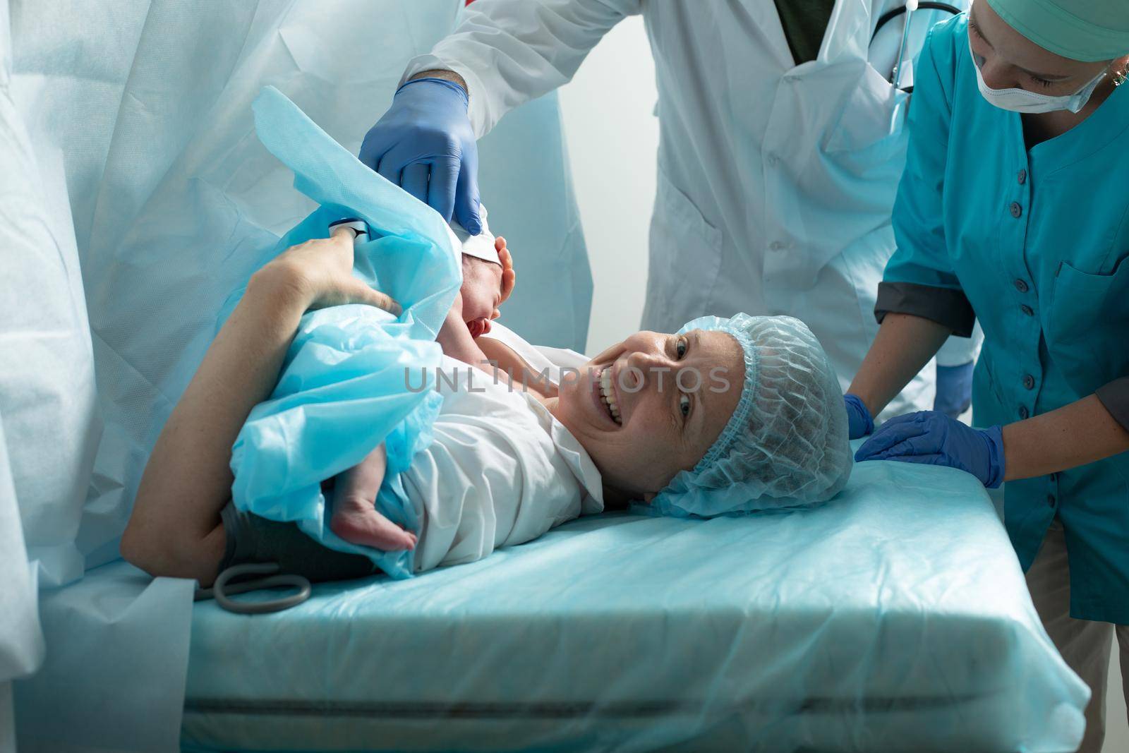 Mother holds newborn baby in hospital, seconds after birth.