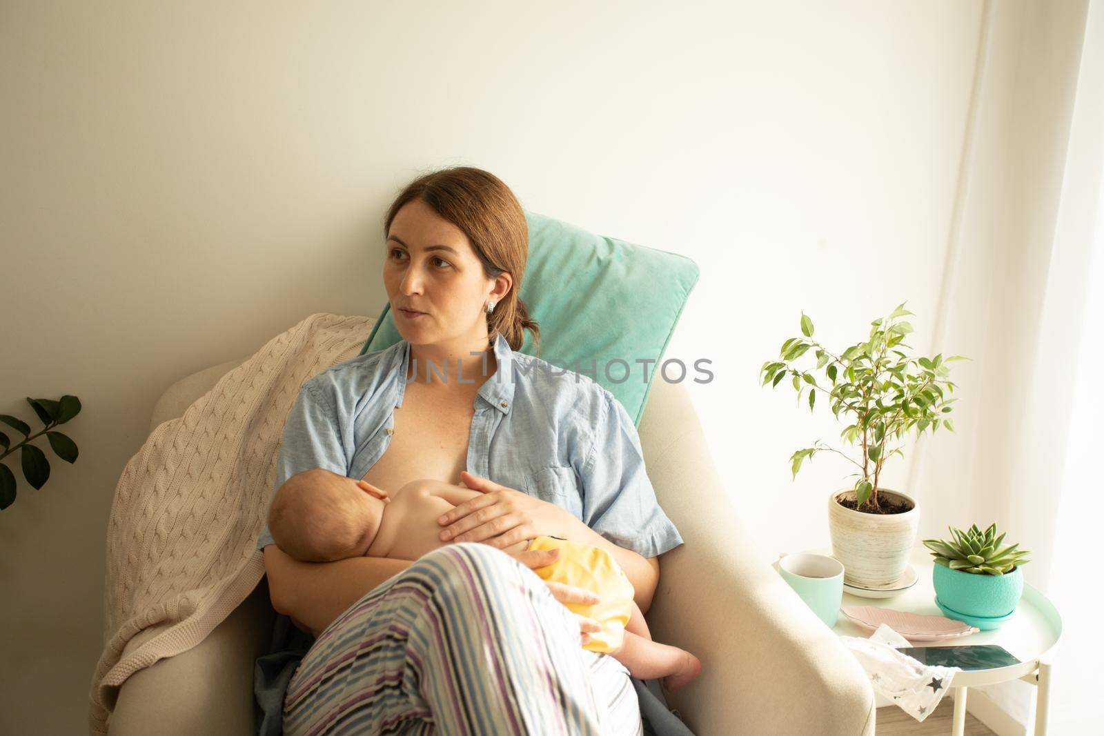 Mothed and baby at the chair. Breastfeeding in cradle position