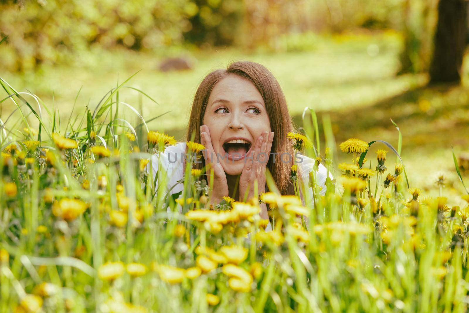 Smiling woman lying at yellow dandelion field