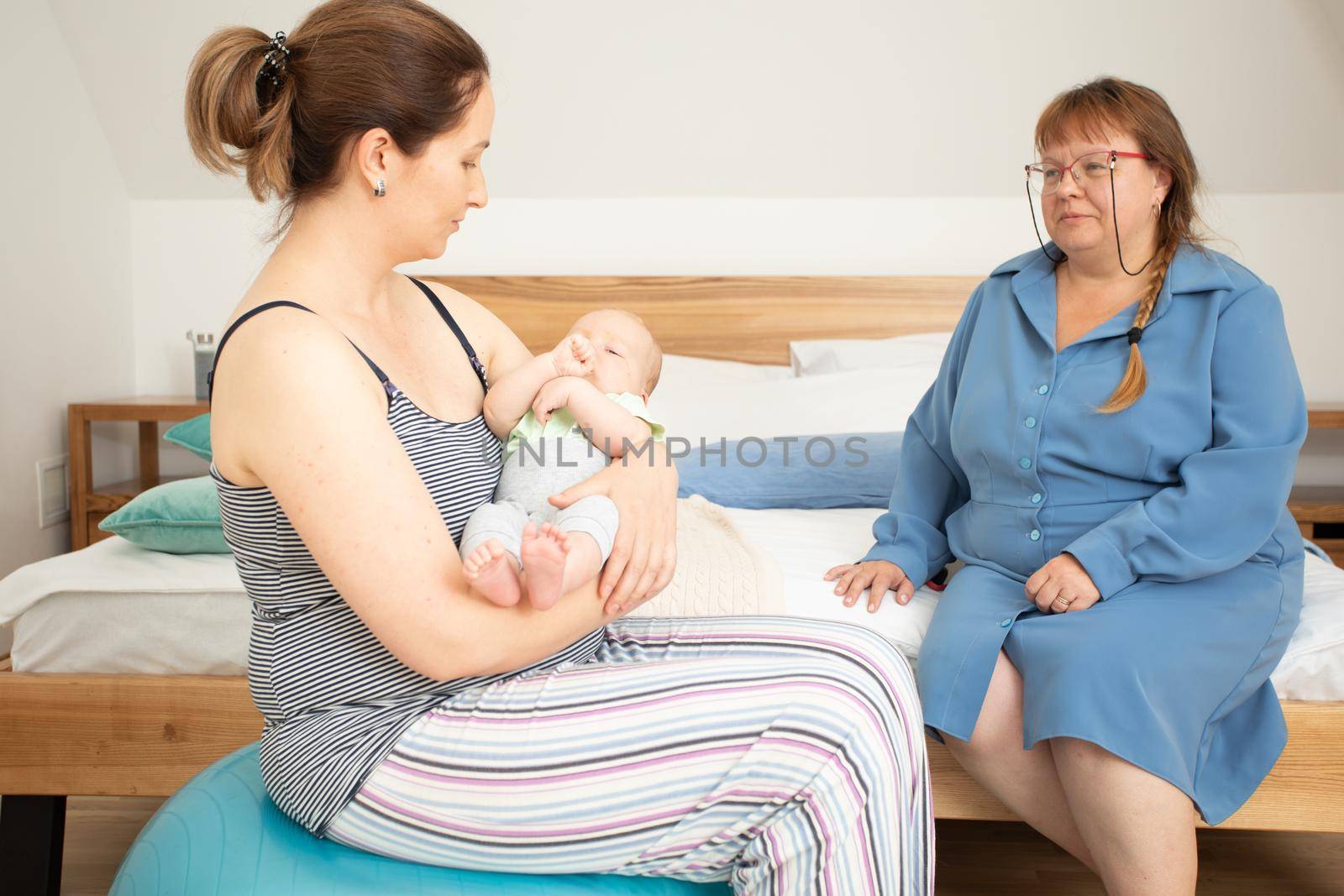 Closeup view newborn baby breastfeeding. Young mother learning how to hold baby, lactation consultant supports mother, helping to adjust baby for comfortable and effectife feeding.