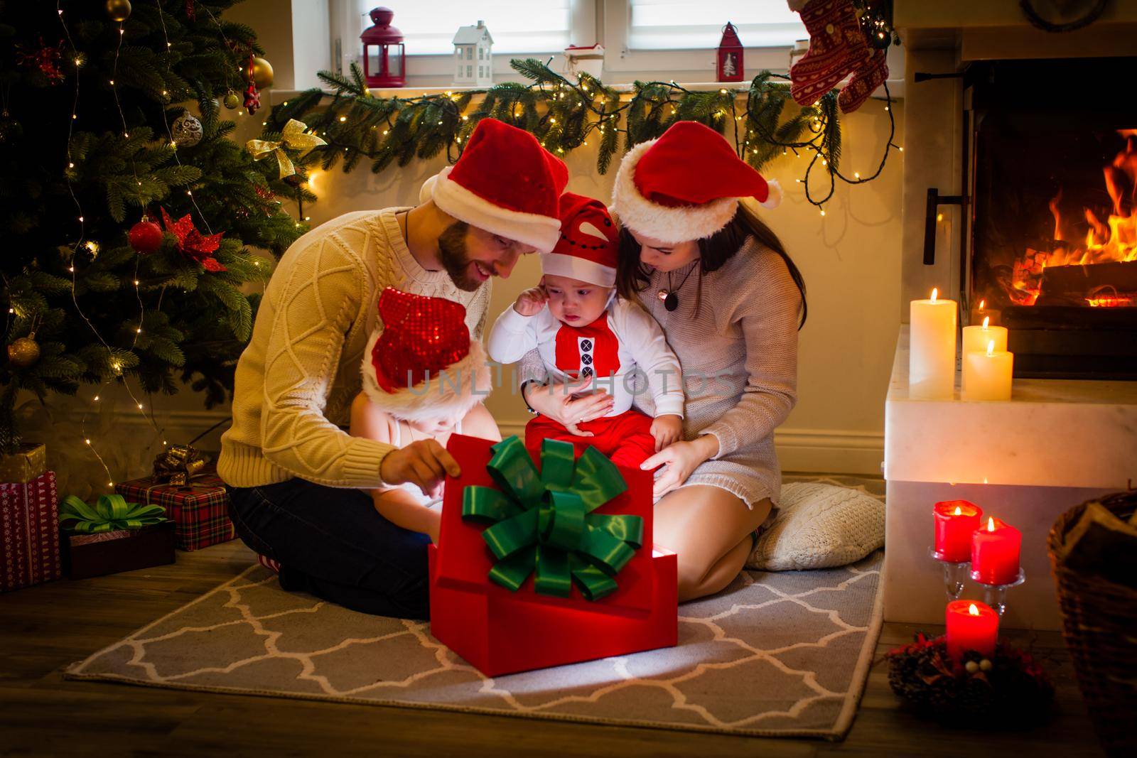 Happy family mother father and children with magic gift near tree near the fireplace at Chriasmtas time