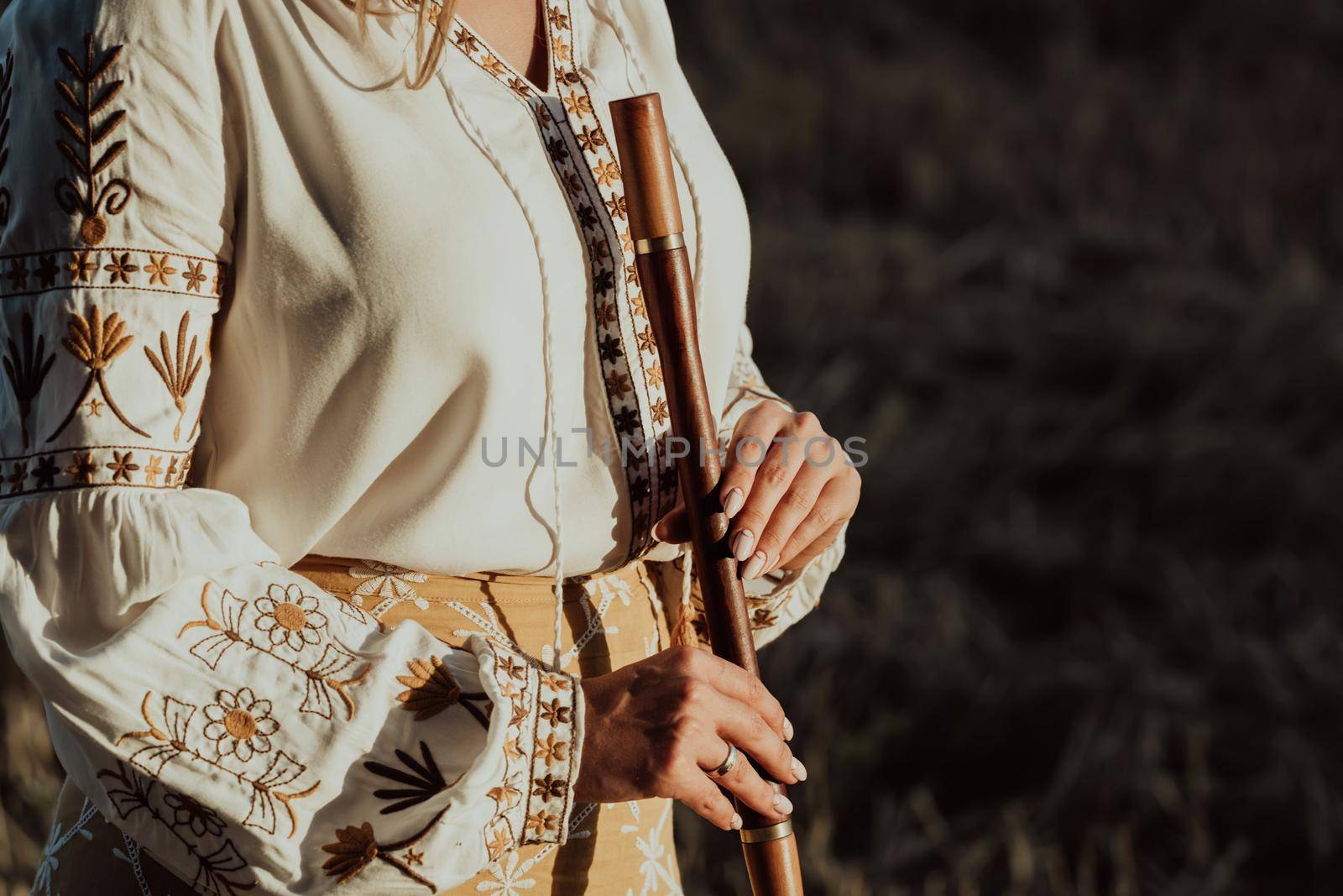 Woman holding woodwind wooden flute - ukrainian telenka or tylynka. Folk music concept. Musical instrument. Musician in traditional embroidered shirt - Vyshyvanka. High quality photo