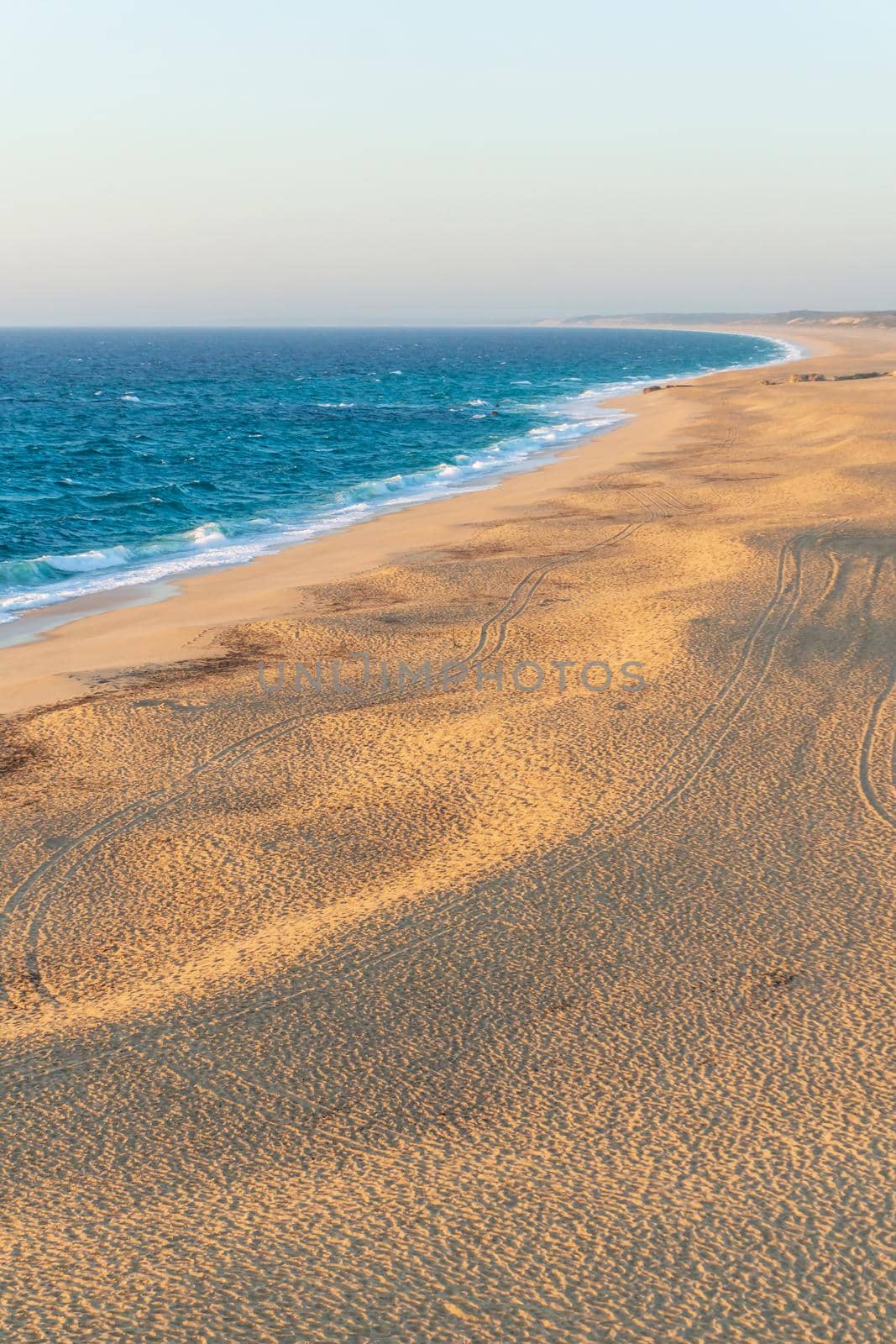 Deserted sandy beach of the atlantic ocean in the rays of the setting sun top view