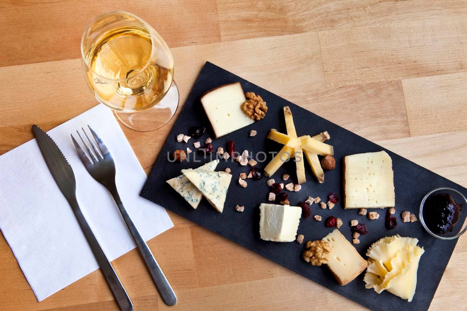 Various cheese on a slate plate and glass of white wine in a French bistro