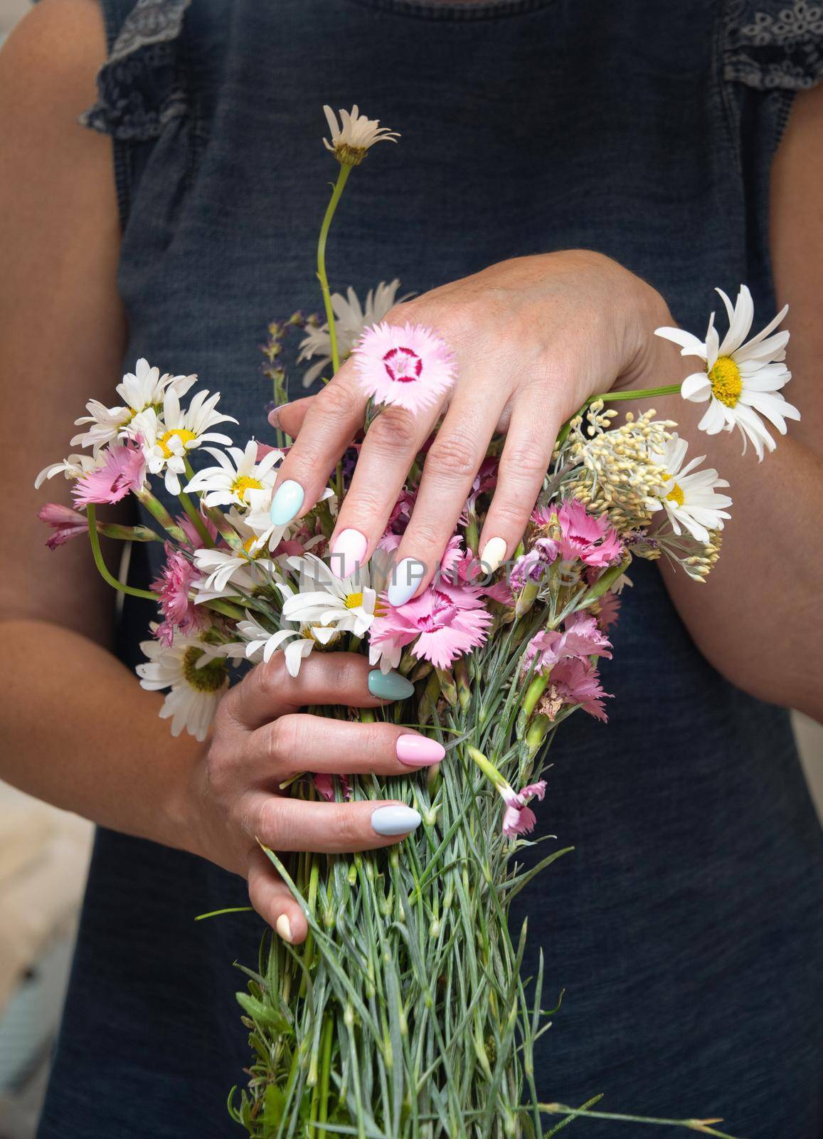 a young woman with a beautiful summer manicure holds a bouquet of wild flowers by KaterinaDalemans