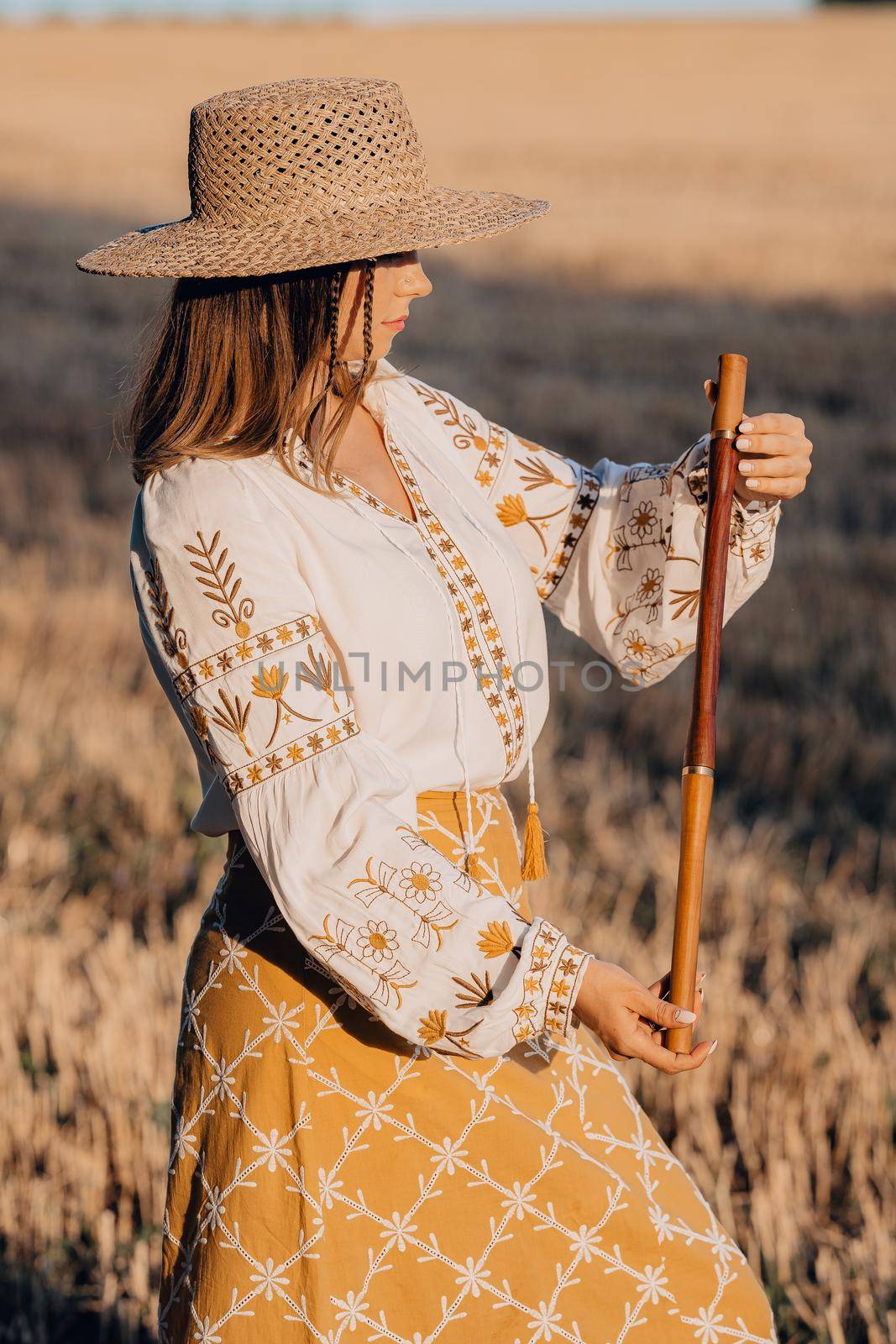 Woman holding woodwind wooden flute - ukrainian telenka or tylynka. Folk music concept. Musical instrument. Musician in traditional embroidered shirt - Vyshyvanka. High quality photo