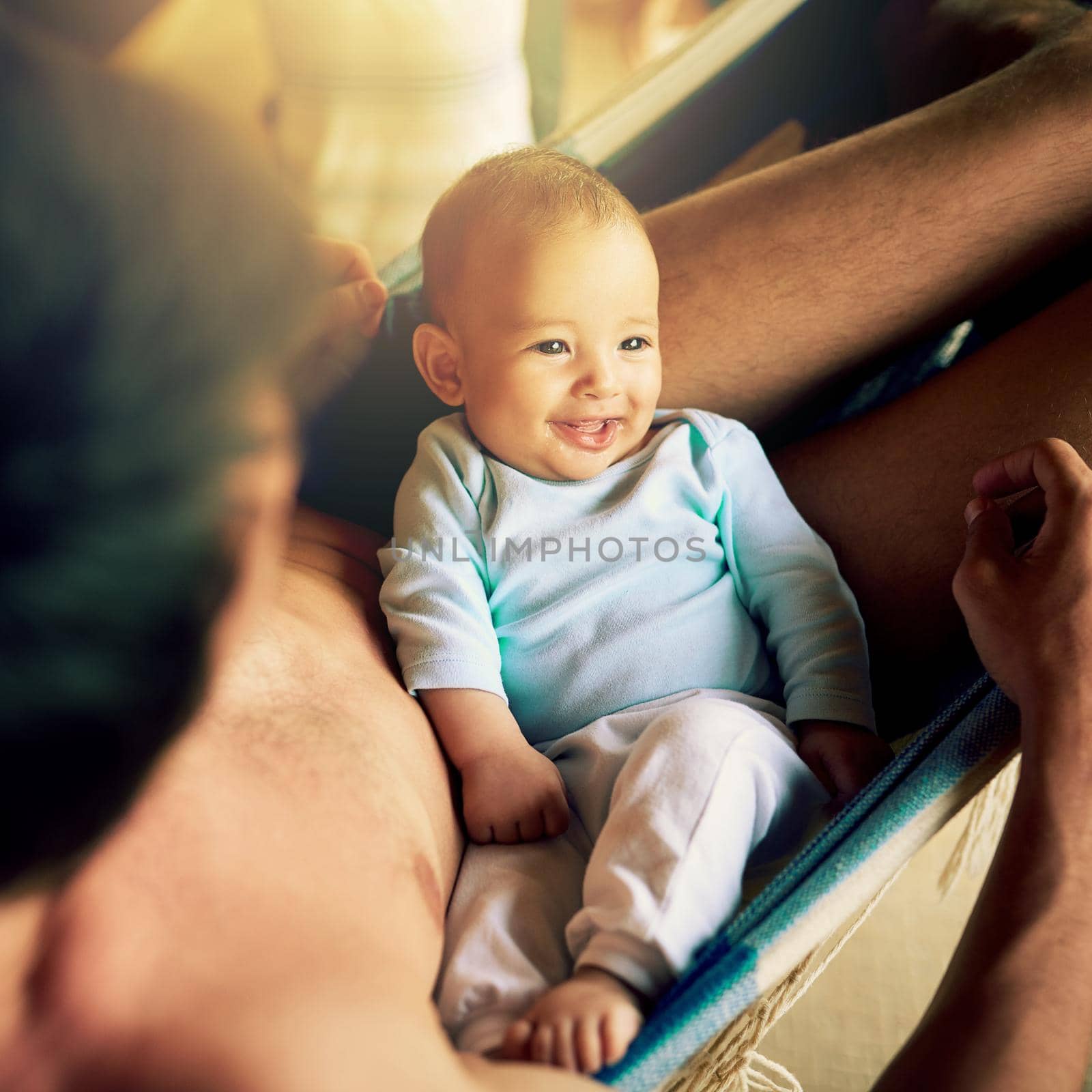 He is going to have a bright future. a cheerful baby boy seated on his fathers lap while looking at the camera outside at home during the day. by YuriArcurs