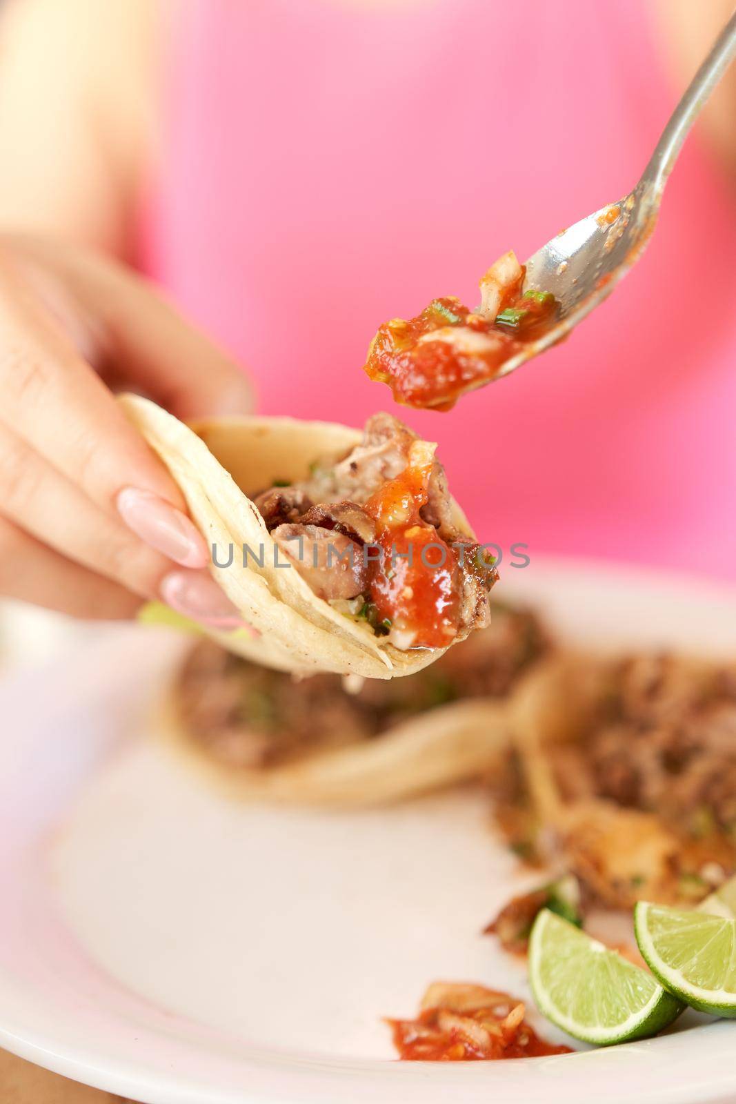 Girl eating delicious taco with salsa and a variety of toppings by JpRamos