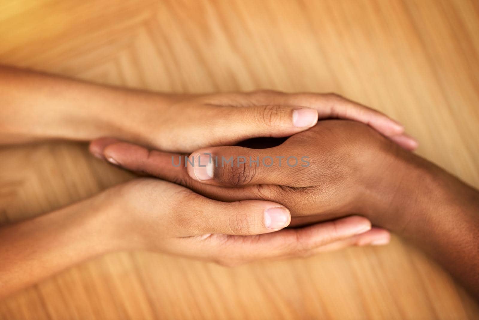 You are not alone. two unrecognizable people holding hands while being seated at a table inside during the day