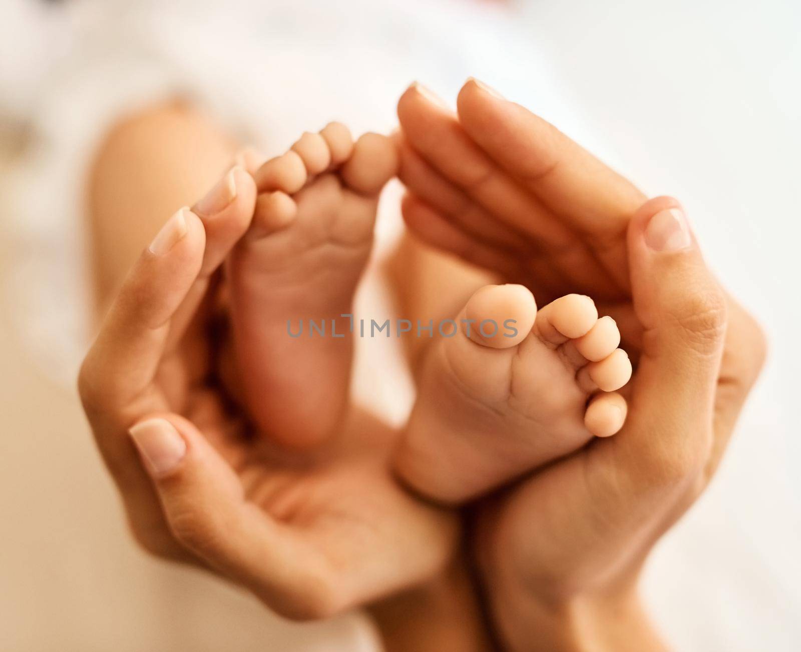 The tiny feet that made her life complete. a mother gently holding her babys feet. by YuriArcurs
