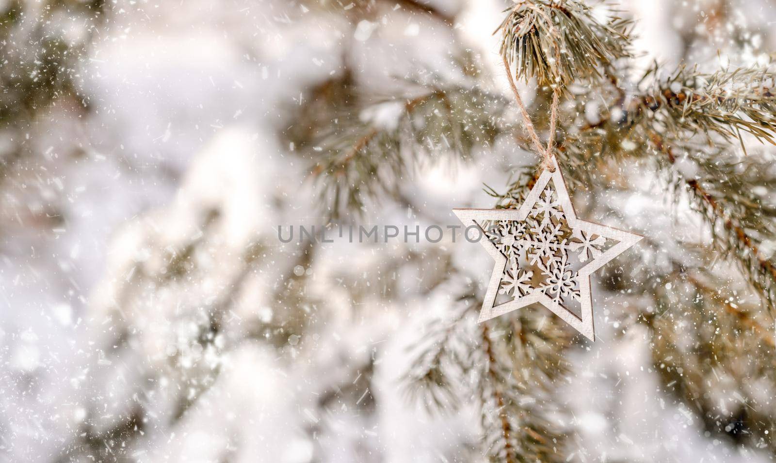 Christmas tree decoration in snow forest in winer time outdoors. Festive star on branch in cold weather with snowflakes
