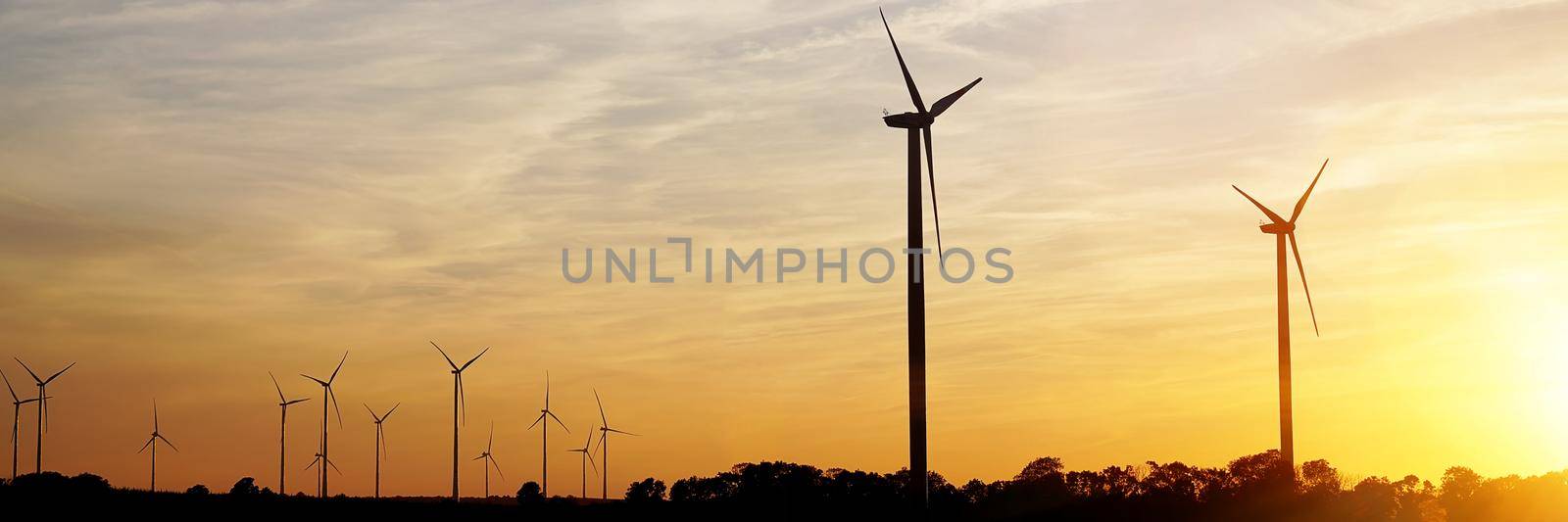 Beautiful sunset above the windmills on the field by PhotoTime