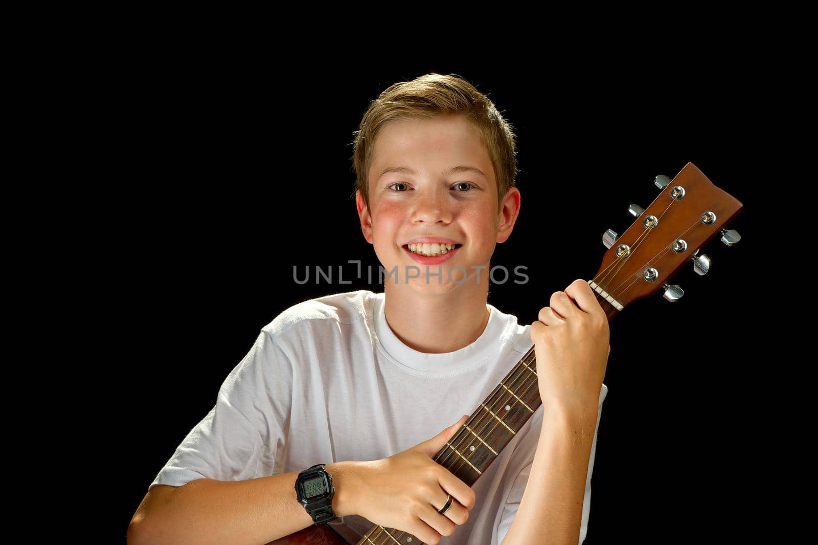 Happy boy playing on acoustic guitar. Teenager boy with classic wooden guitar. by PhotoTime