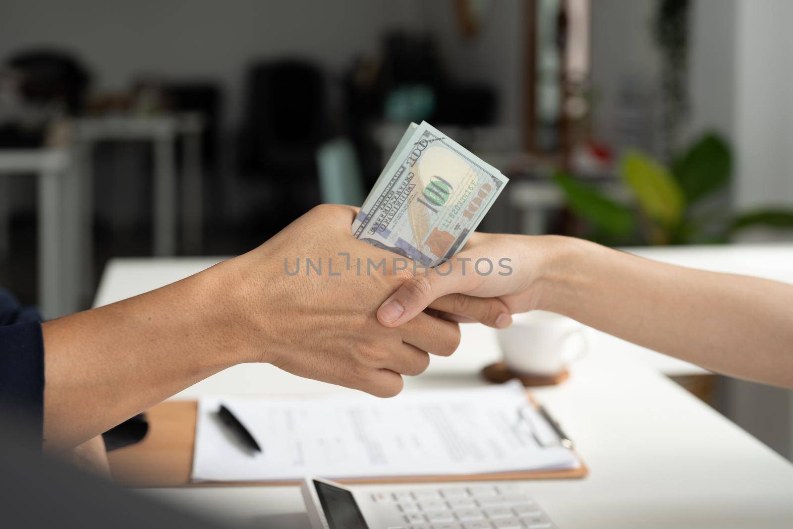 Businessmen making handshake with money in hands - bribery, corruption and venality concepts.