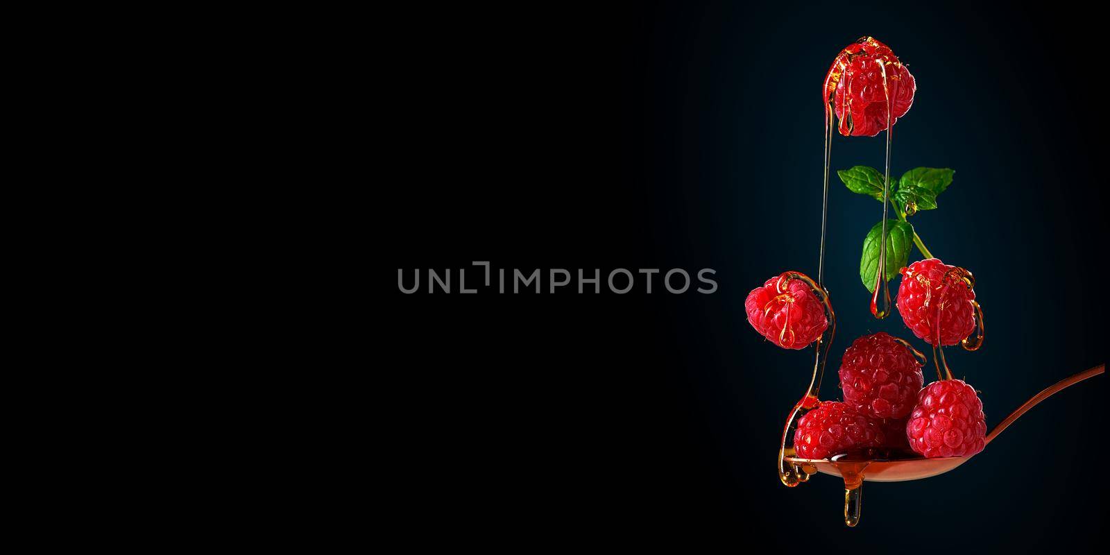 Falling raspberries. food levitation on dark background. ripe raspberries and honey