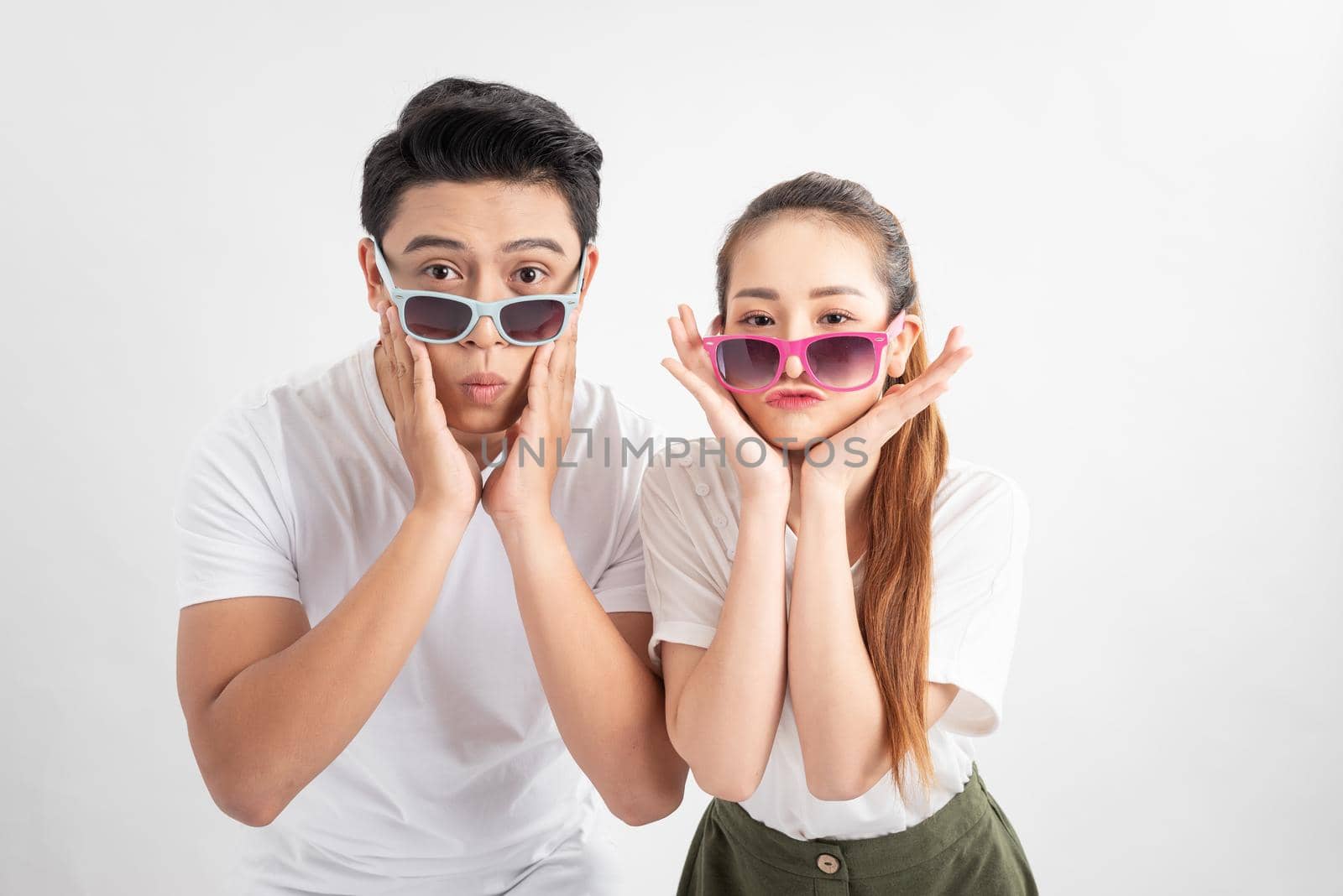 Close-up portrait of two nice attractive adorable cheerful people husband wife in eyeglasses eyewear touches cheeks with both hands over white background by makidotvn