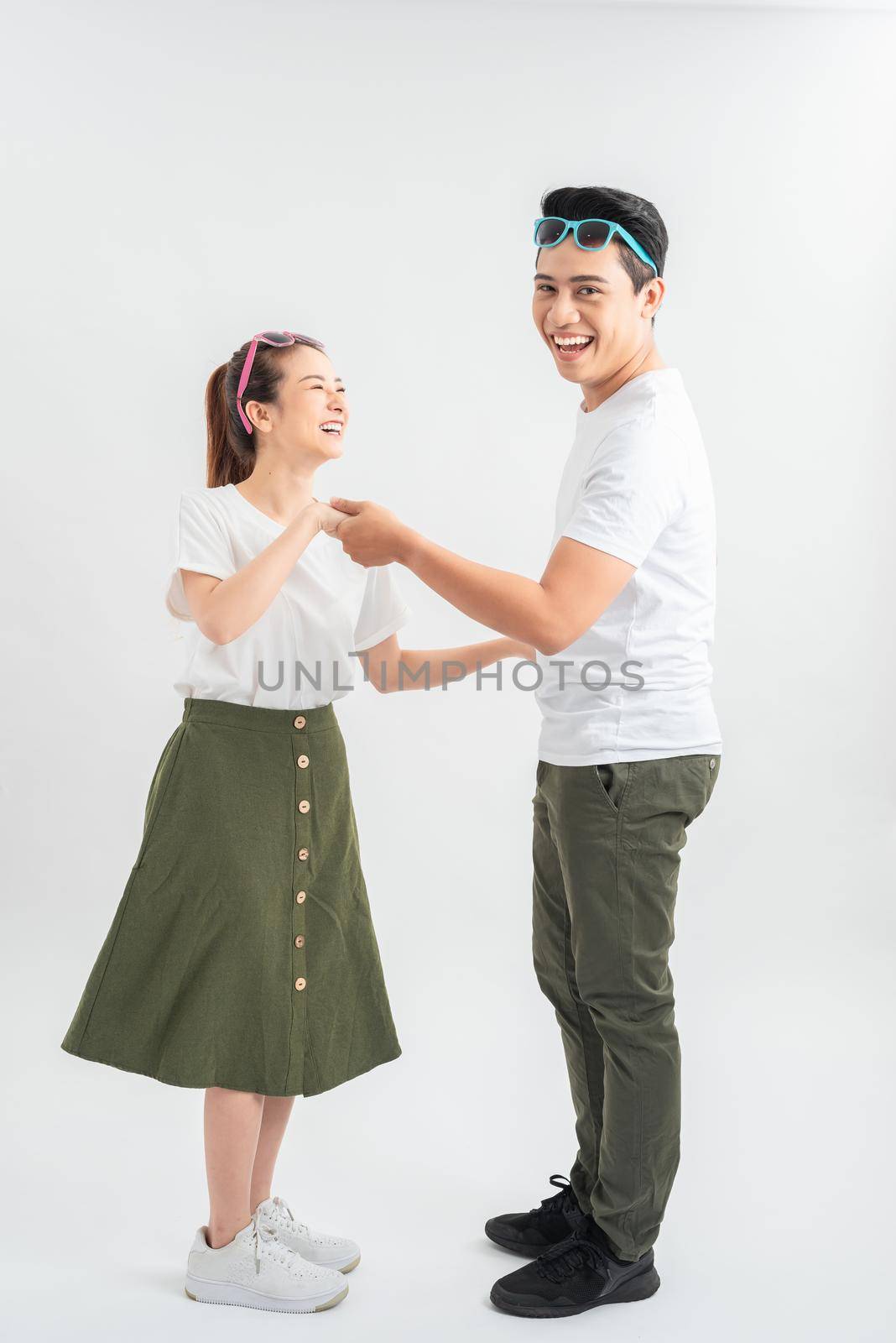 happy young couple in white t-shirts dancing and smiling at camera isolated on white by makidotvn