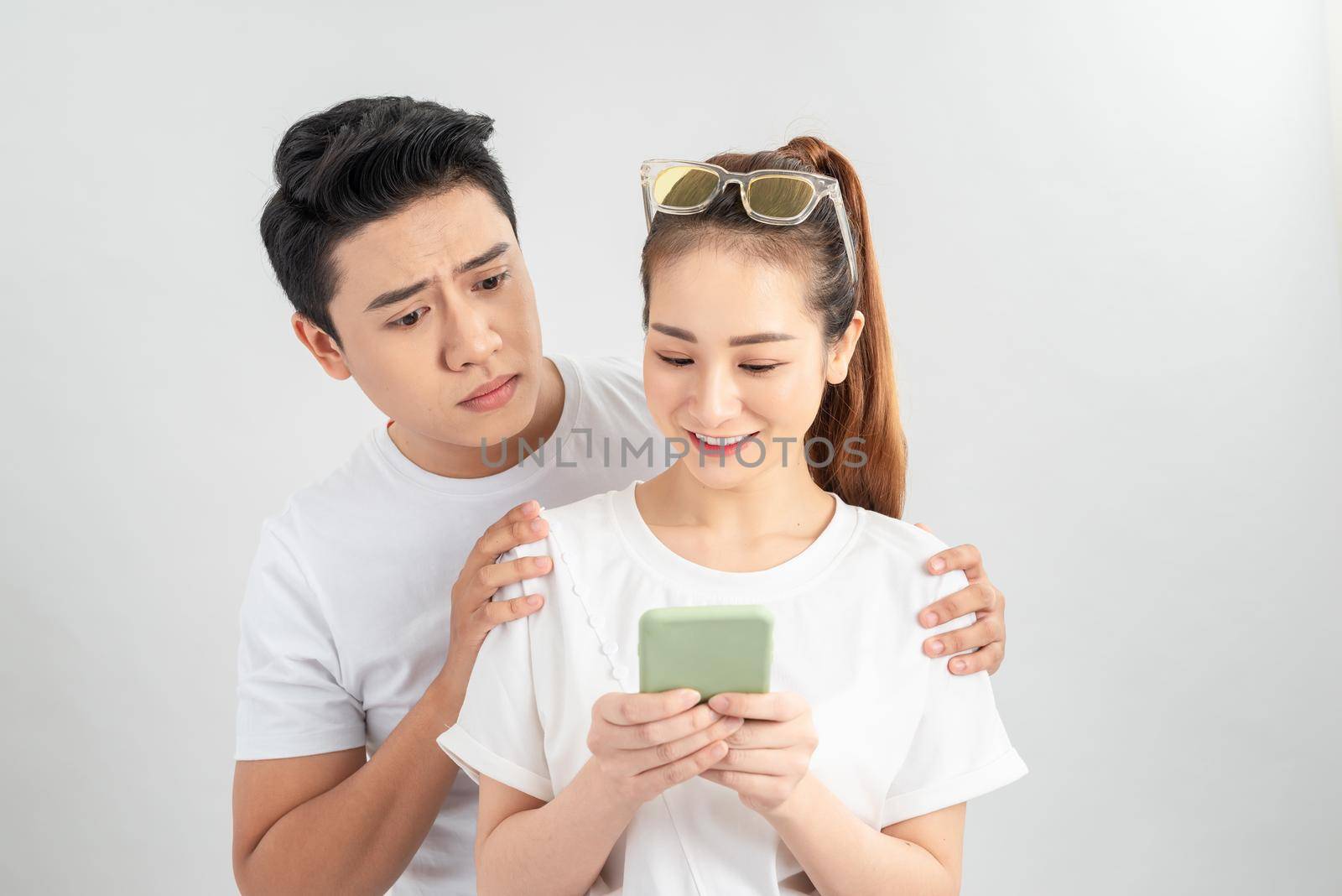 Asian young boy spying on his partner's mobile phone in white background isolated by makidotvn