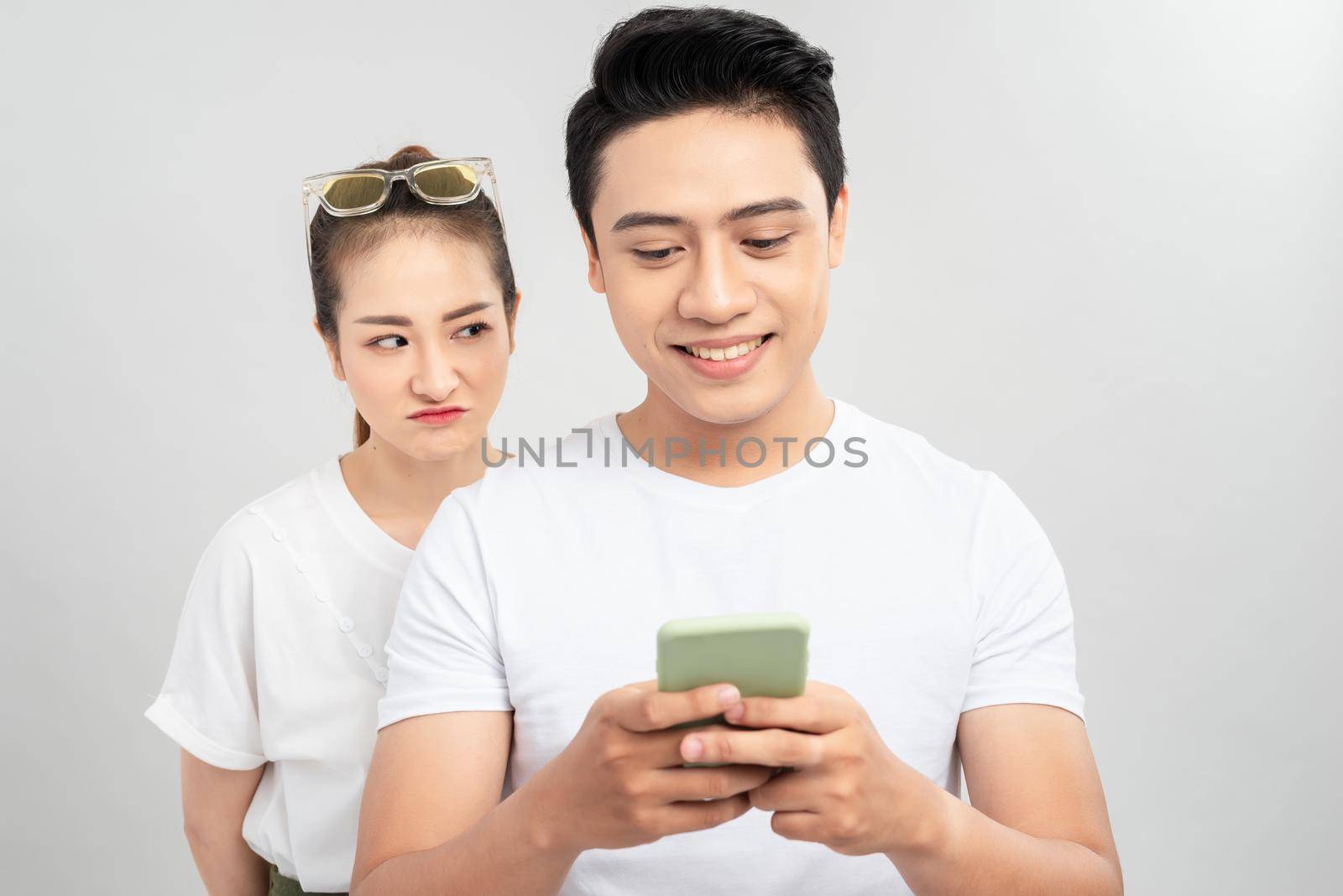Cheater man dating online with a smart phone and girlfriend is spying on white background