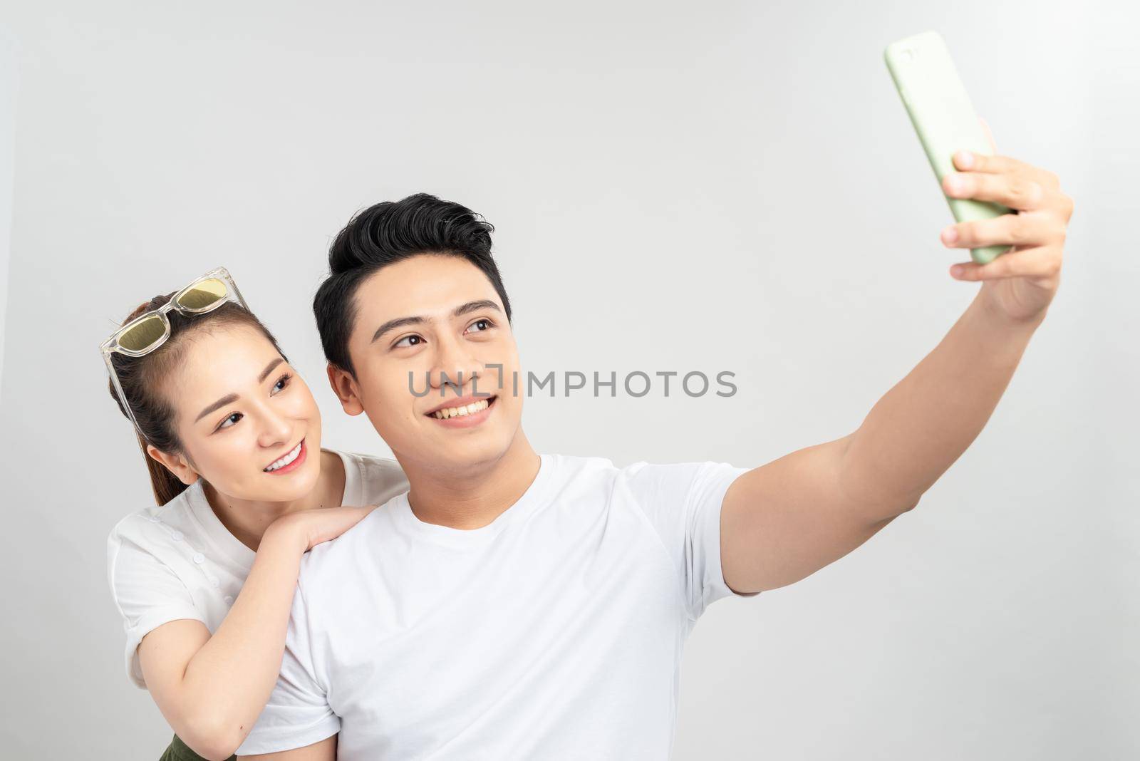 selective focus of happy asian couple taking selfie on smartphone isolated on white by makidotvn