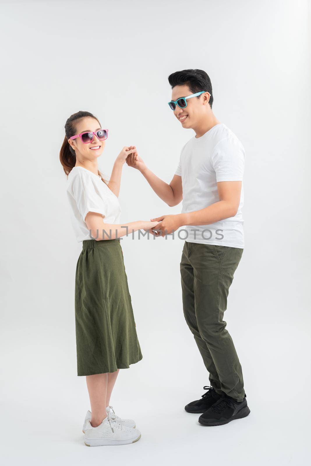 smiling young couple dancing and holding hands, isolated on white