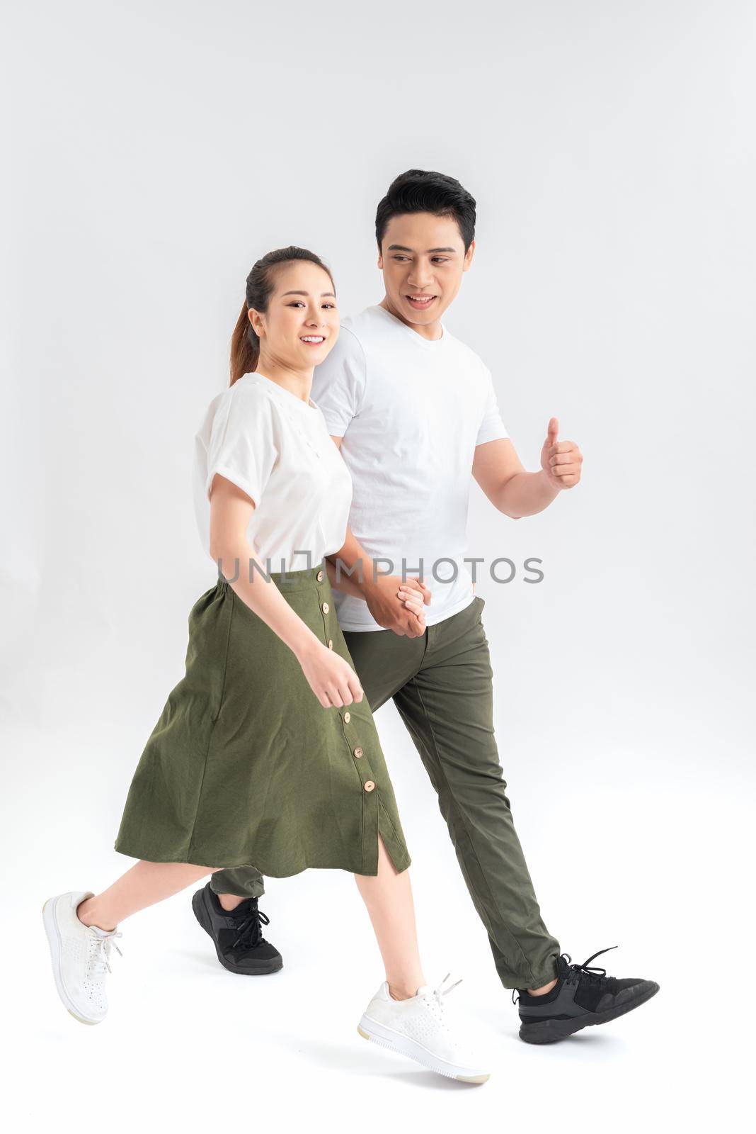 Young couple in casual clothes walking on white background