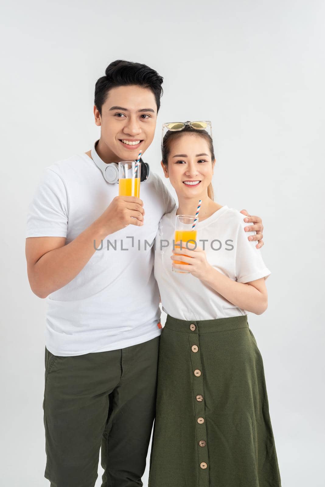 A young couple drink OJ on white background