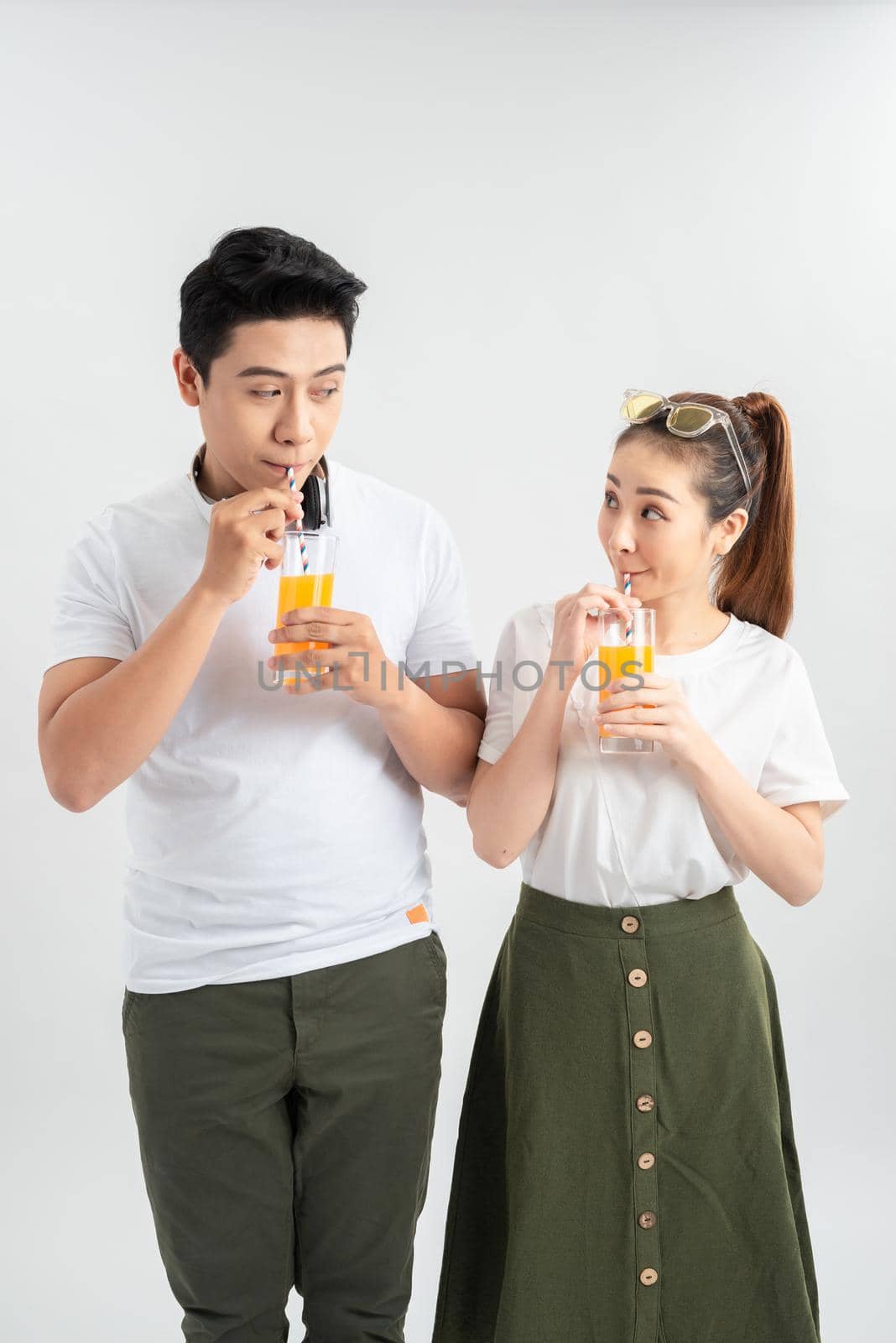 A young pretty Asian couple with a glasses of Orange juice by makidotvn