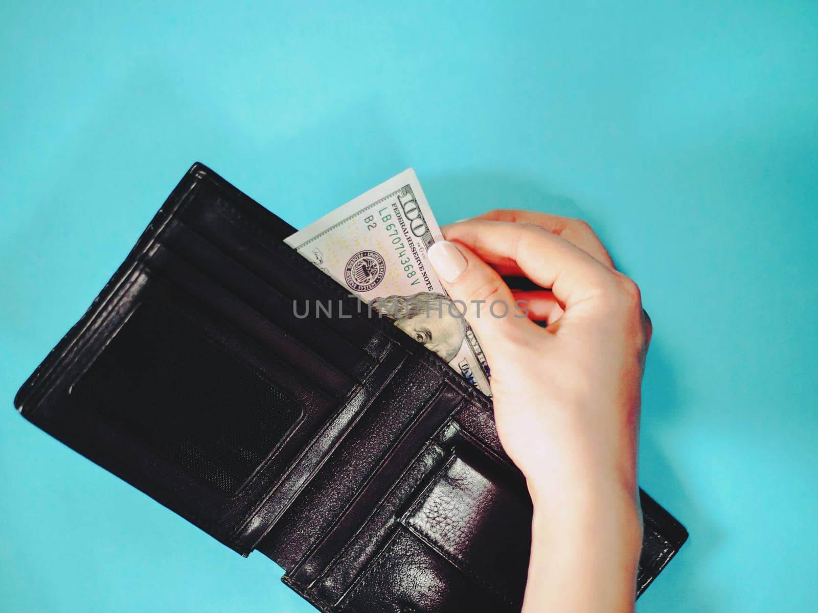 Female hand holding dollars in wallet on blue desk. close up.