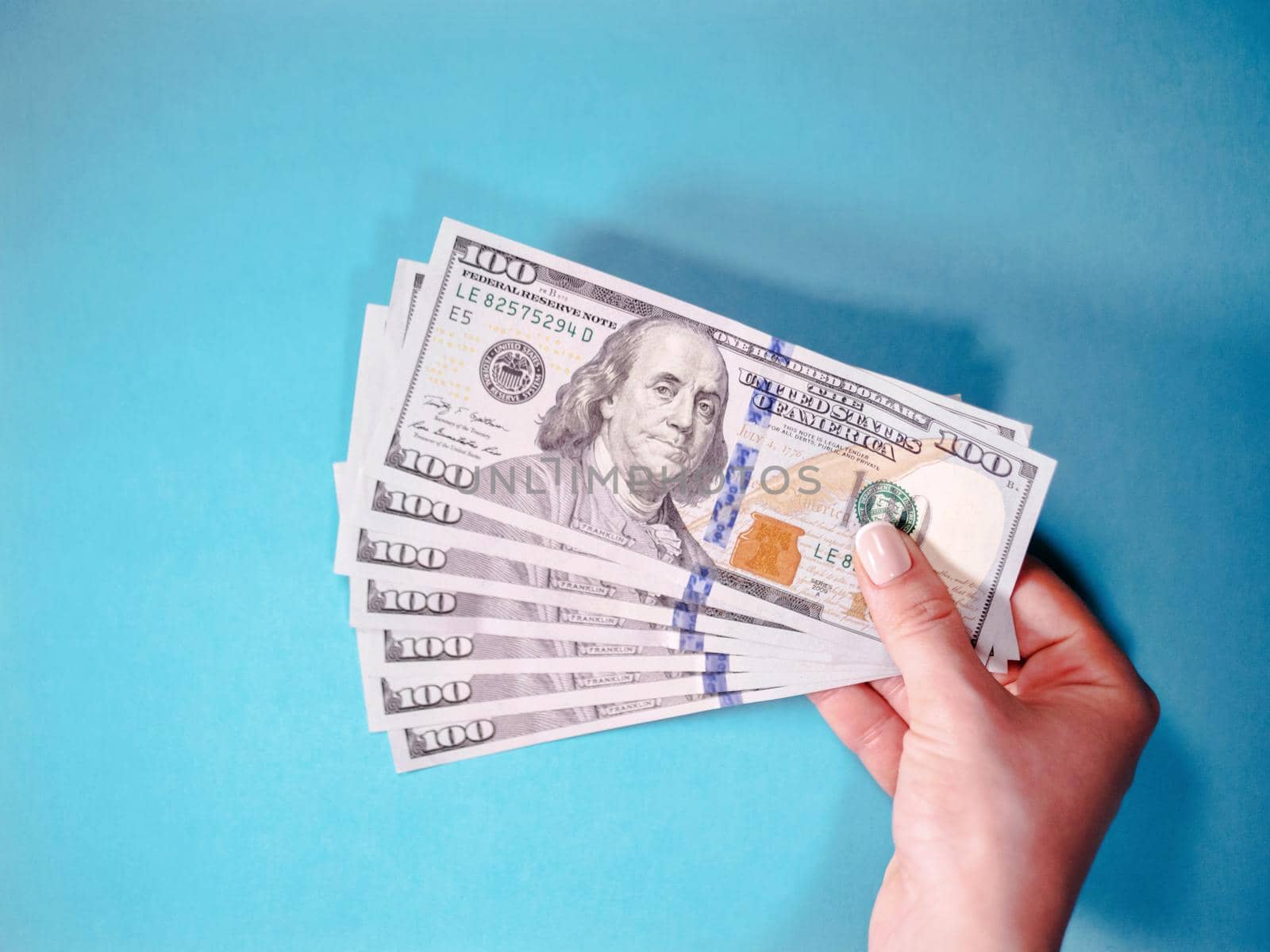 Woman's hand with money isolated on a blue background