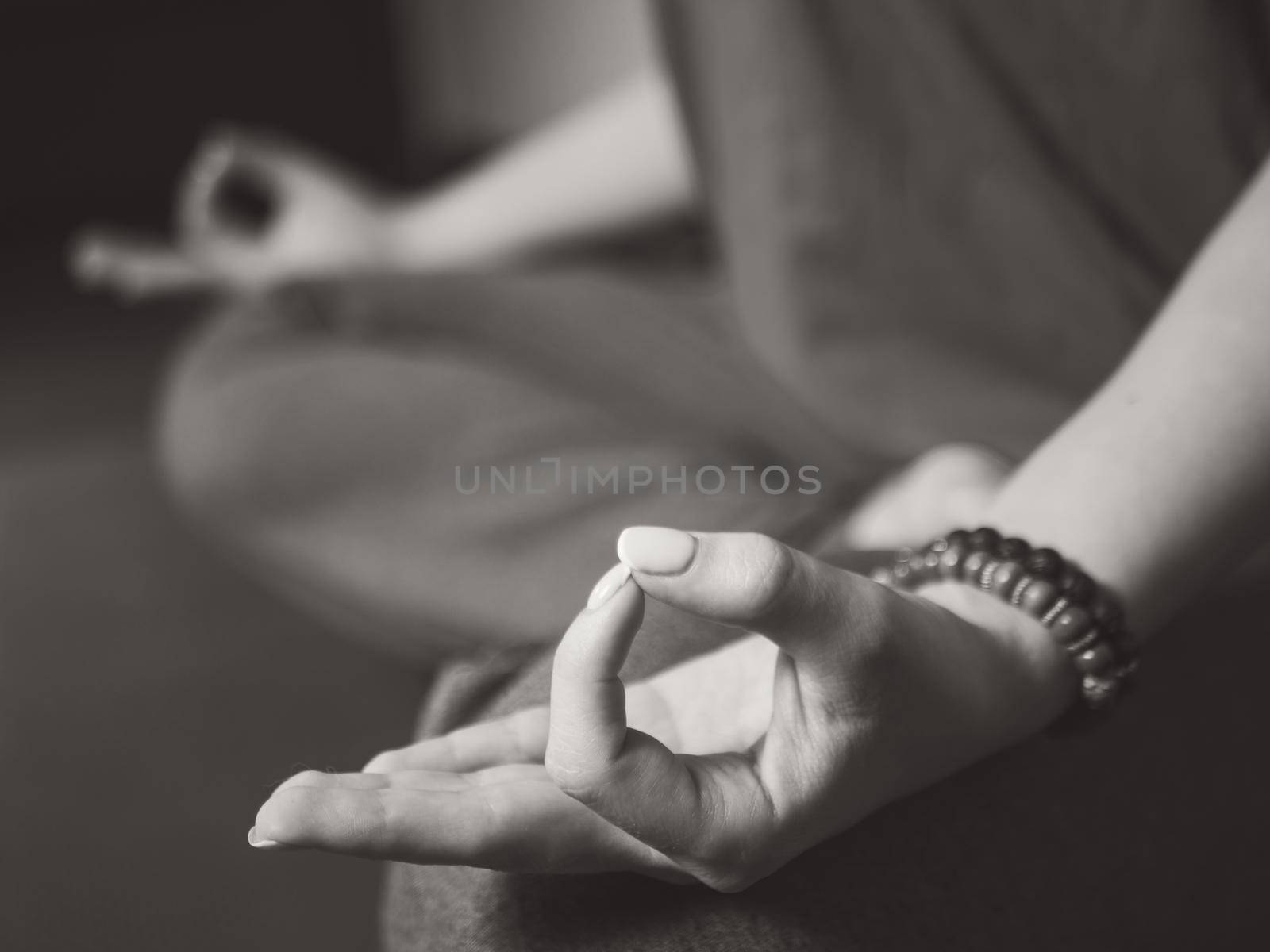 Closeup of woman's hands with bracelets meditating in lotus pose indoors. Gyan mudra. Yoga, religion concept.